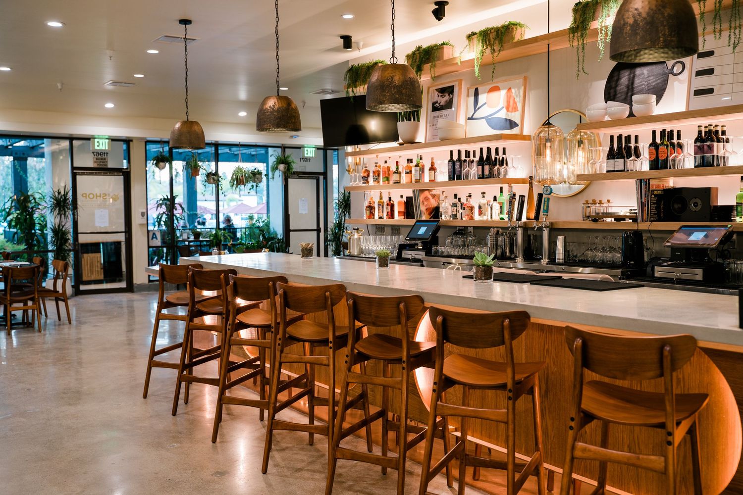 Warm, moody bar atmosphere at a The Shop pizzeria featuring wine bottles and modern california decor