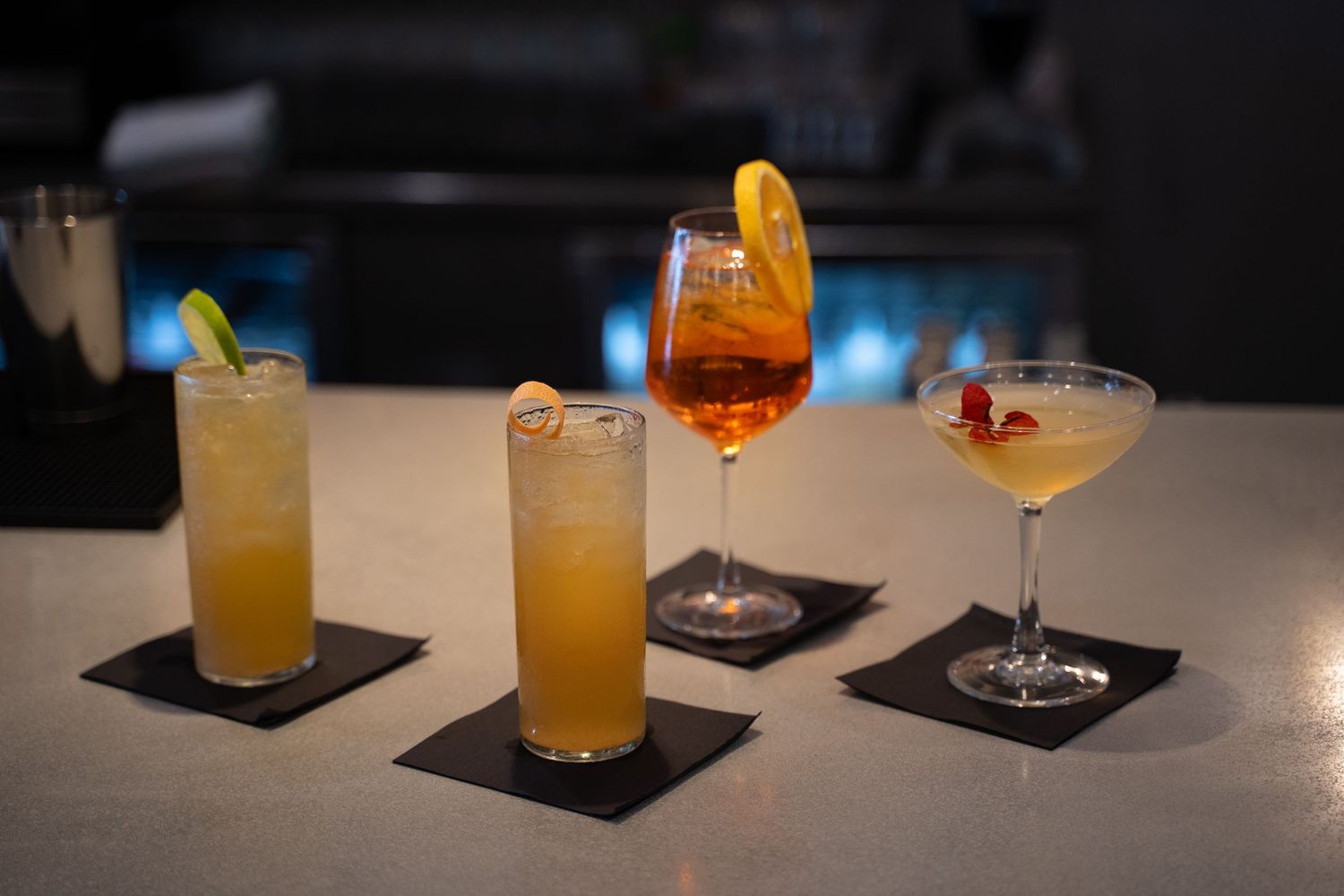 A quartet of craft cocktails on a moody bar, ready for the weekend