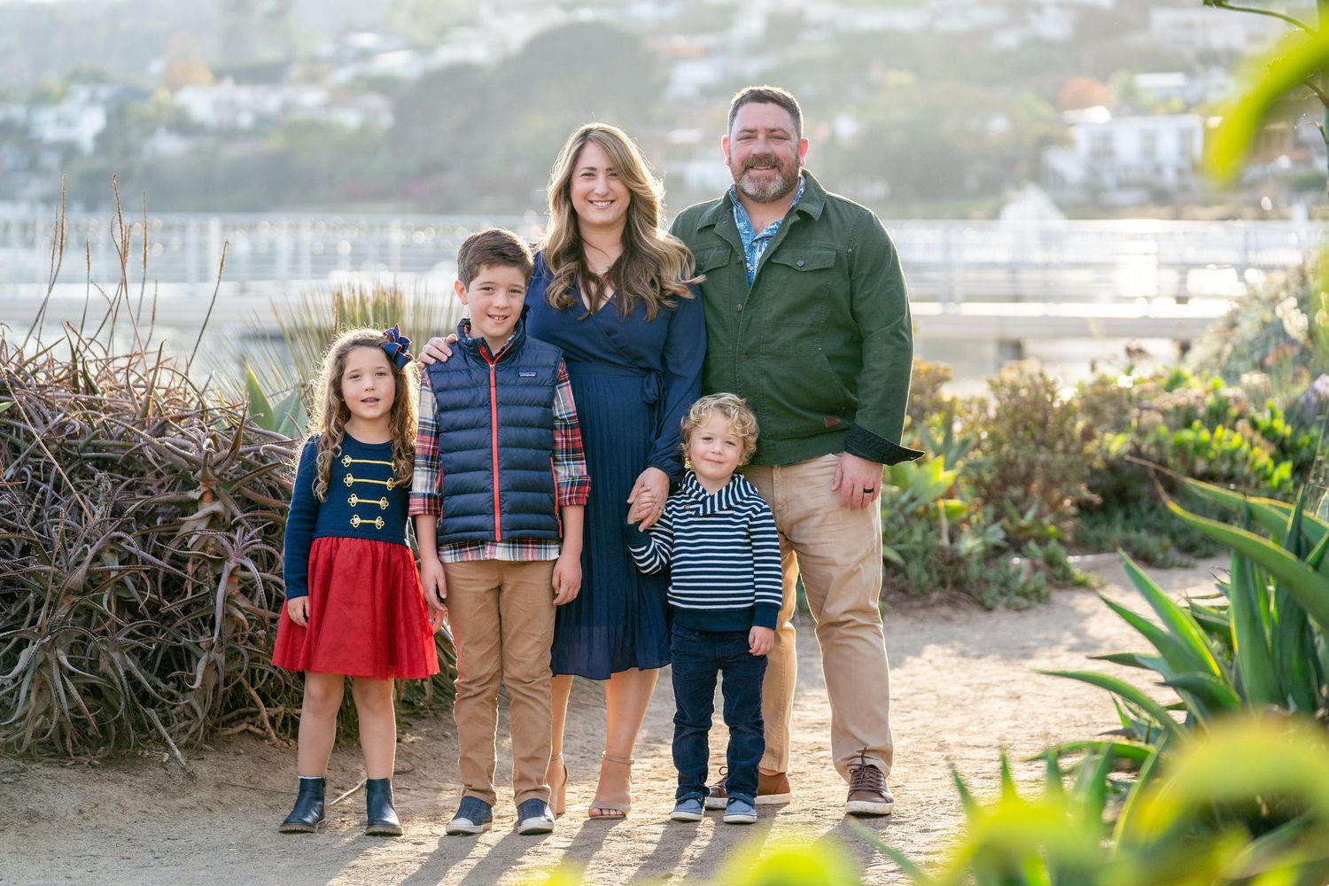 Smiling family of five with coastal background and afternoon glow – Southern California bay front session