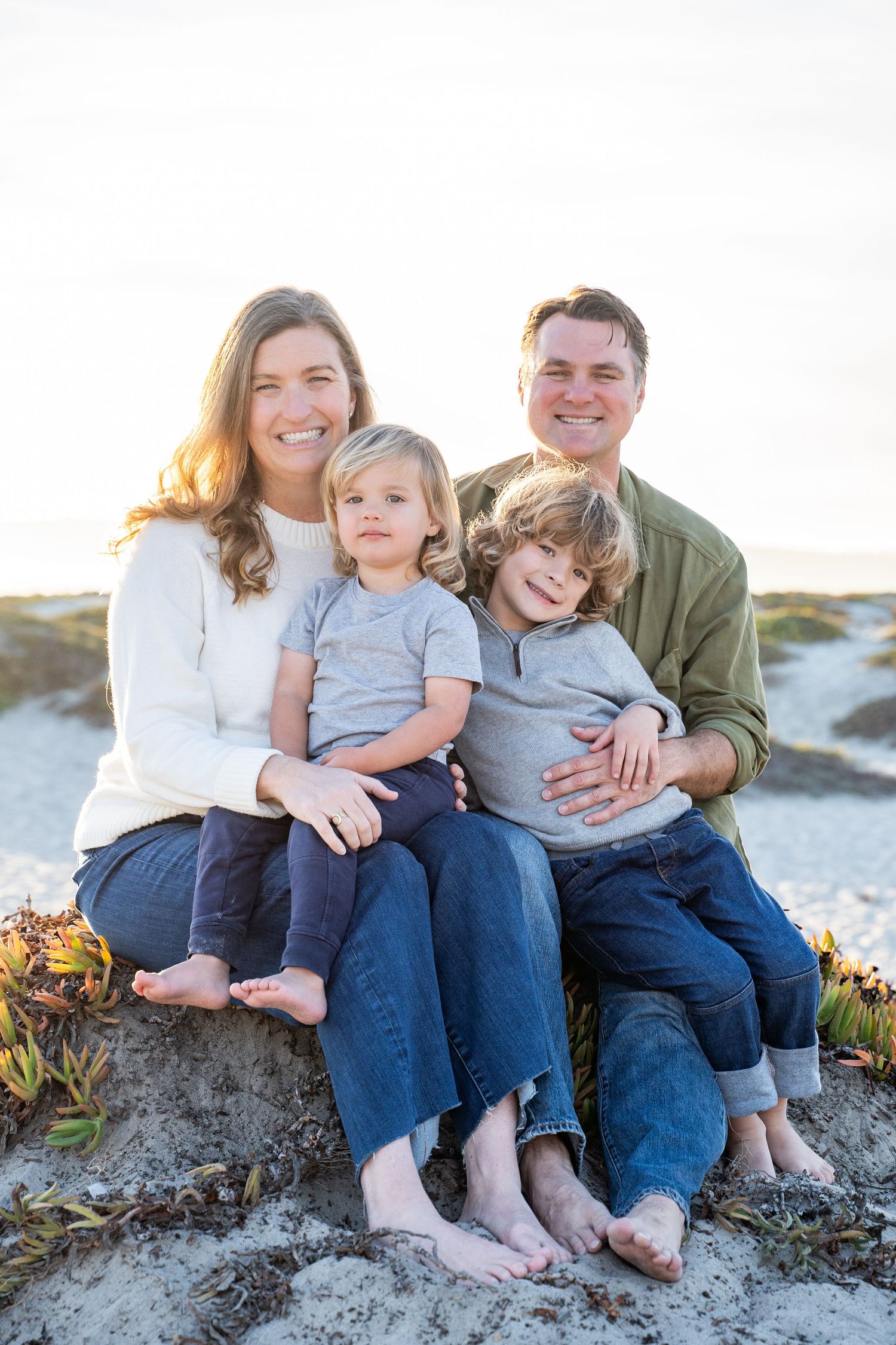 Parents and two children laughing together on the sand dunes – Coronado coastal family portrait session