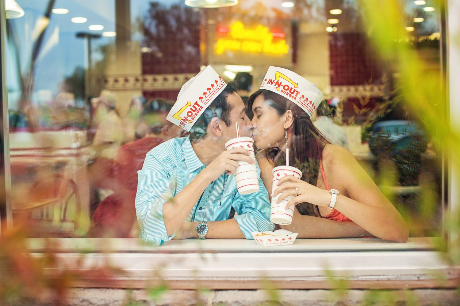 Sweethearts kissing in the glow of In-N-Out’s red and white interior – playful lifestyle couple’s shoot