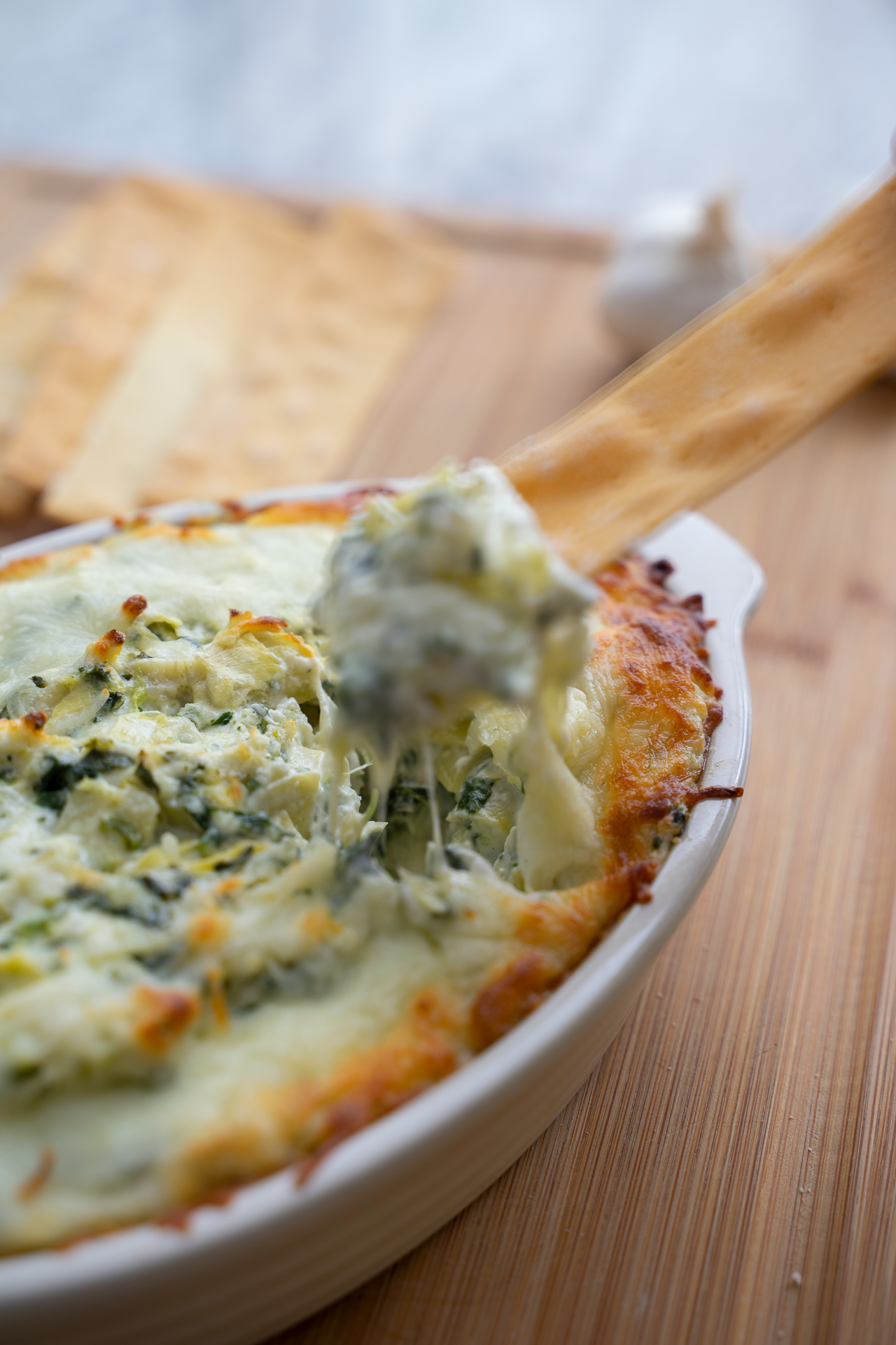 Hot artichoke dip fresh from the oven with toasted baguette slices – styled cookbook photography