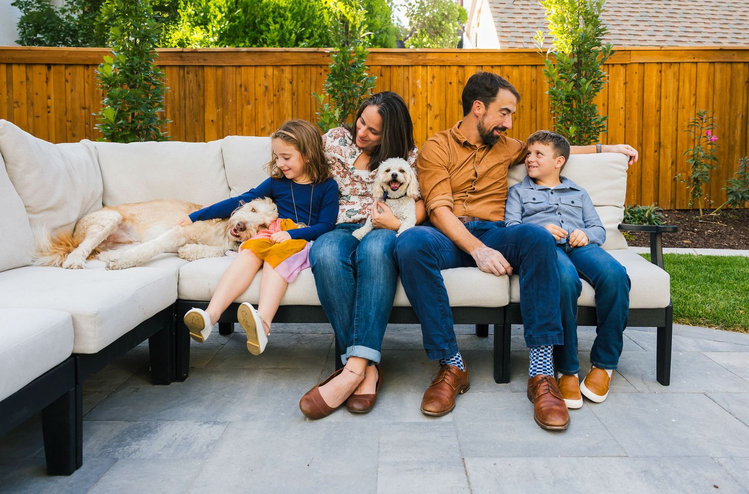 Candid moment of family and pets lounging together on outdoor patio furniture.