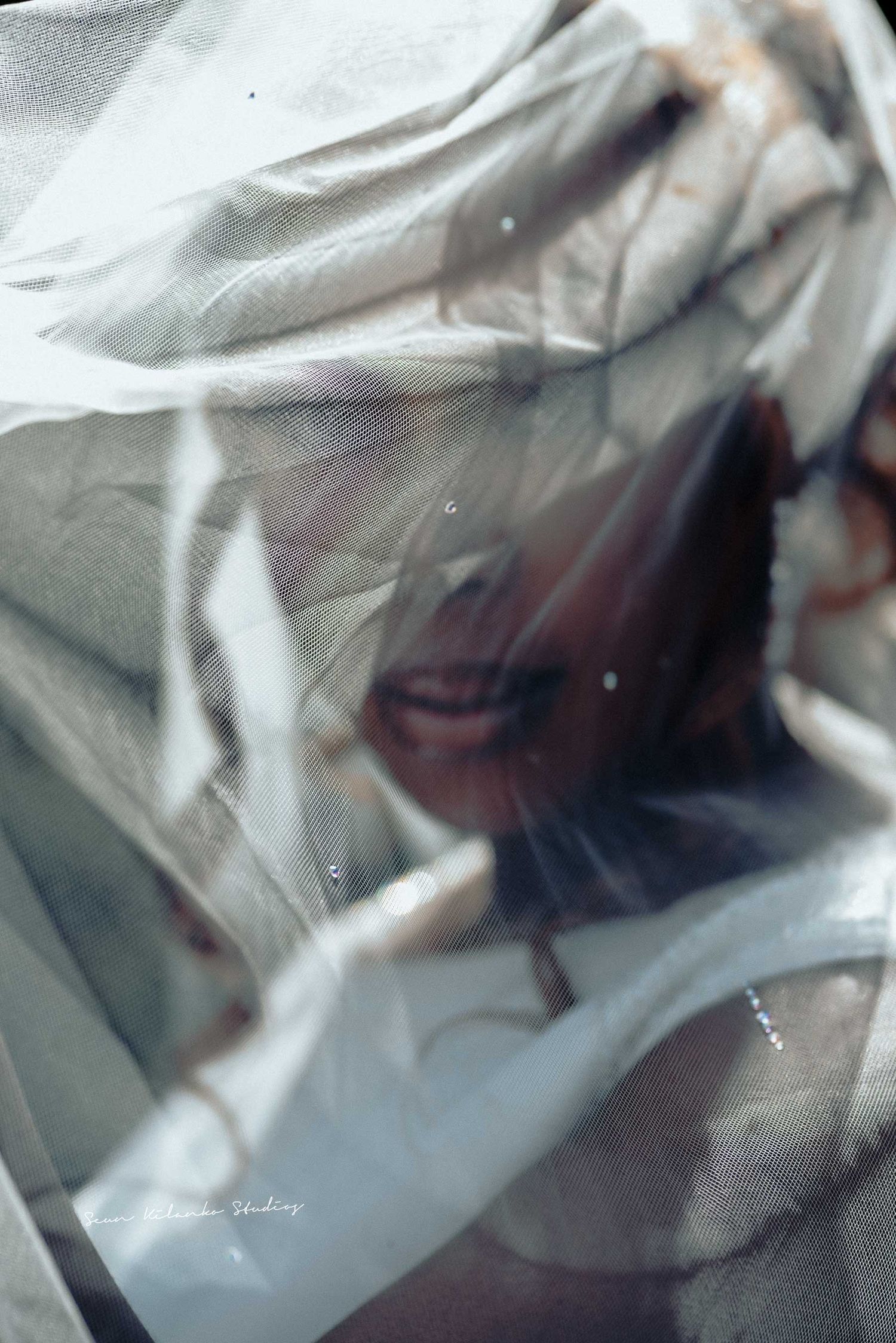 Artistic veiled bridal portrait with dreamy, ethereal lighting effects.