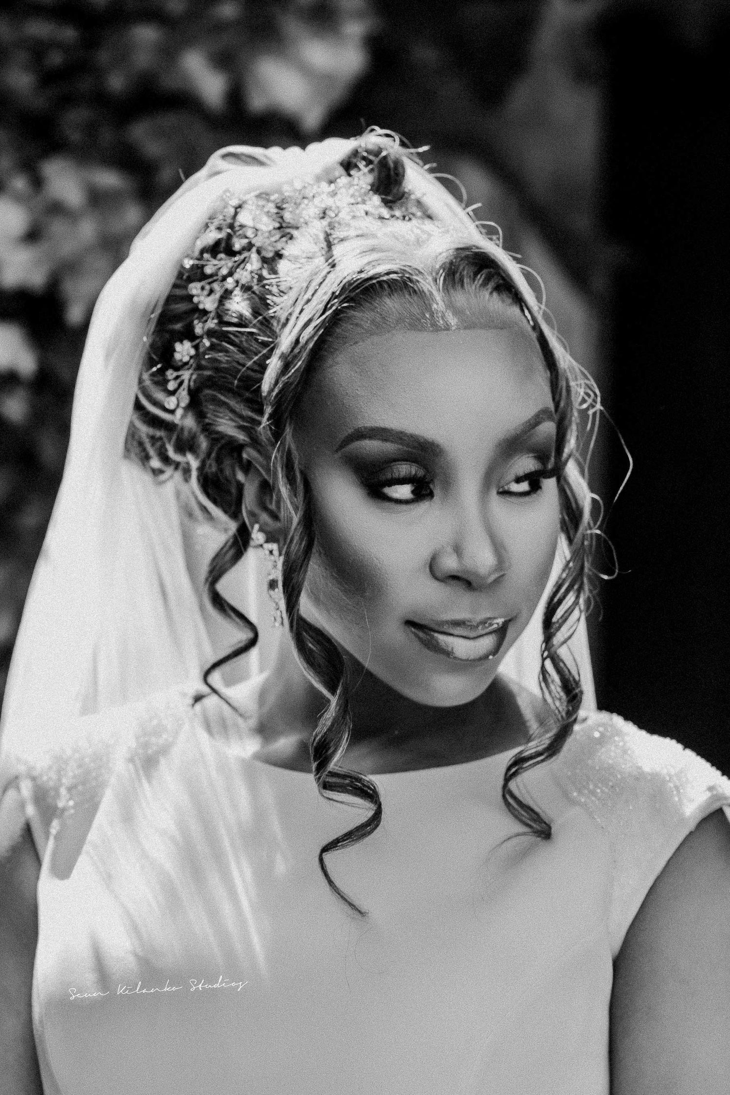 Dramatic black and white bridal portrait with elegant curled hairstyle and flowing veil.