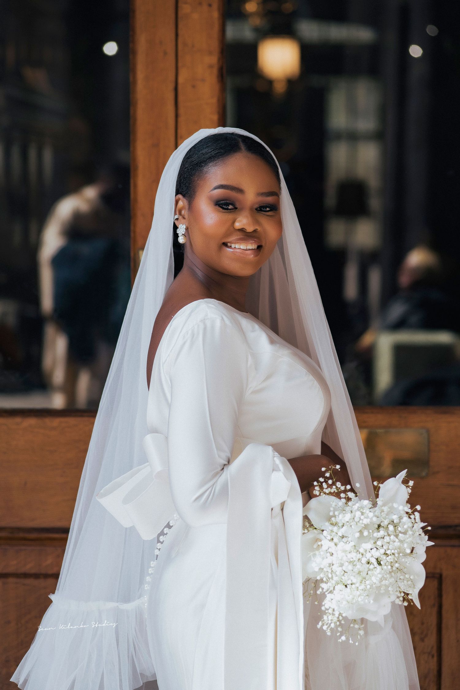 Radiant bride in a long-sleeved white gown holding a delicate baby's breath bouquet.