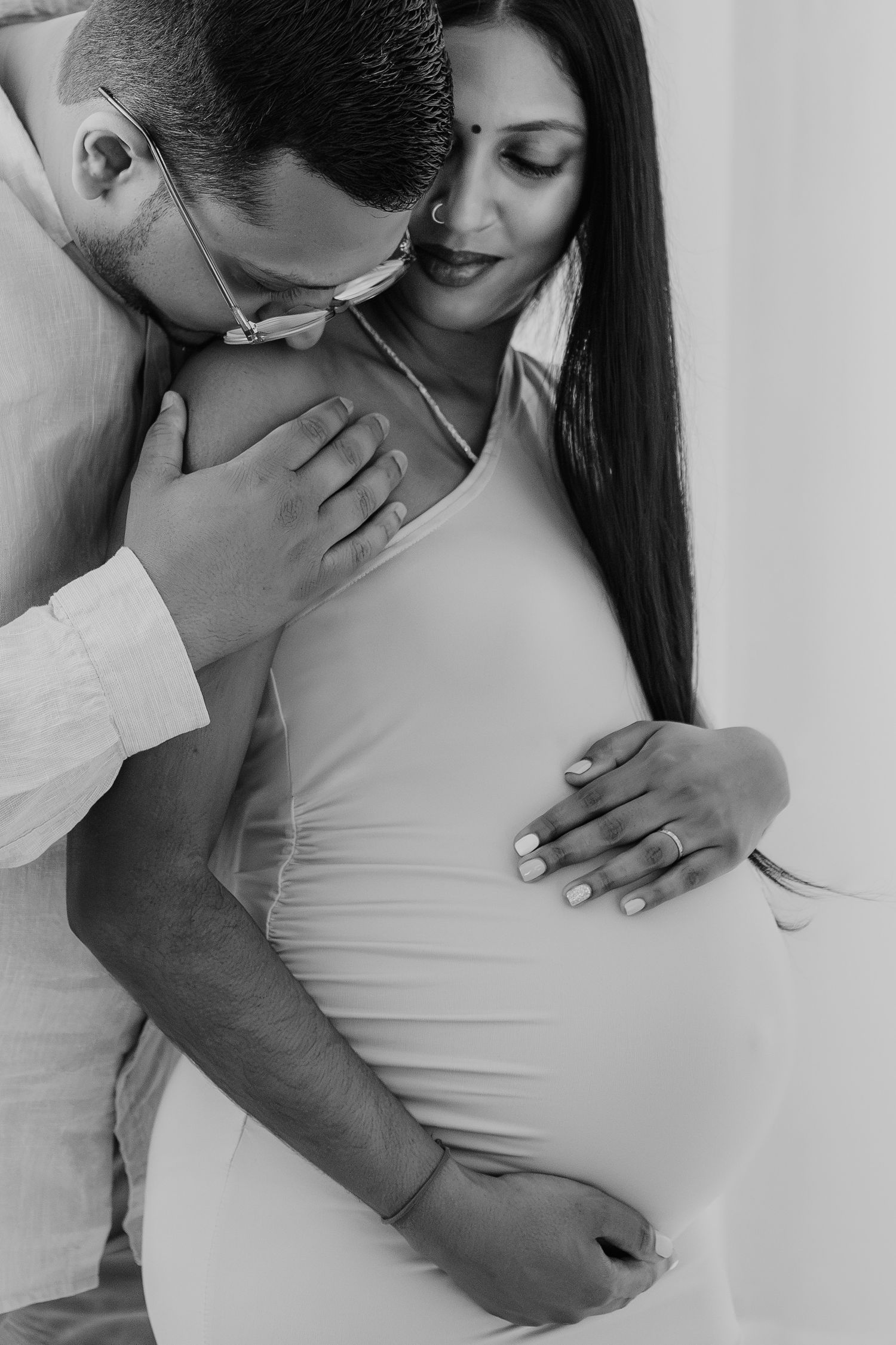 Intimate black and white portrait series showing tender moments against white backdrop.