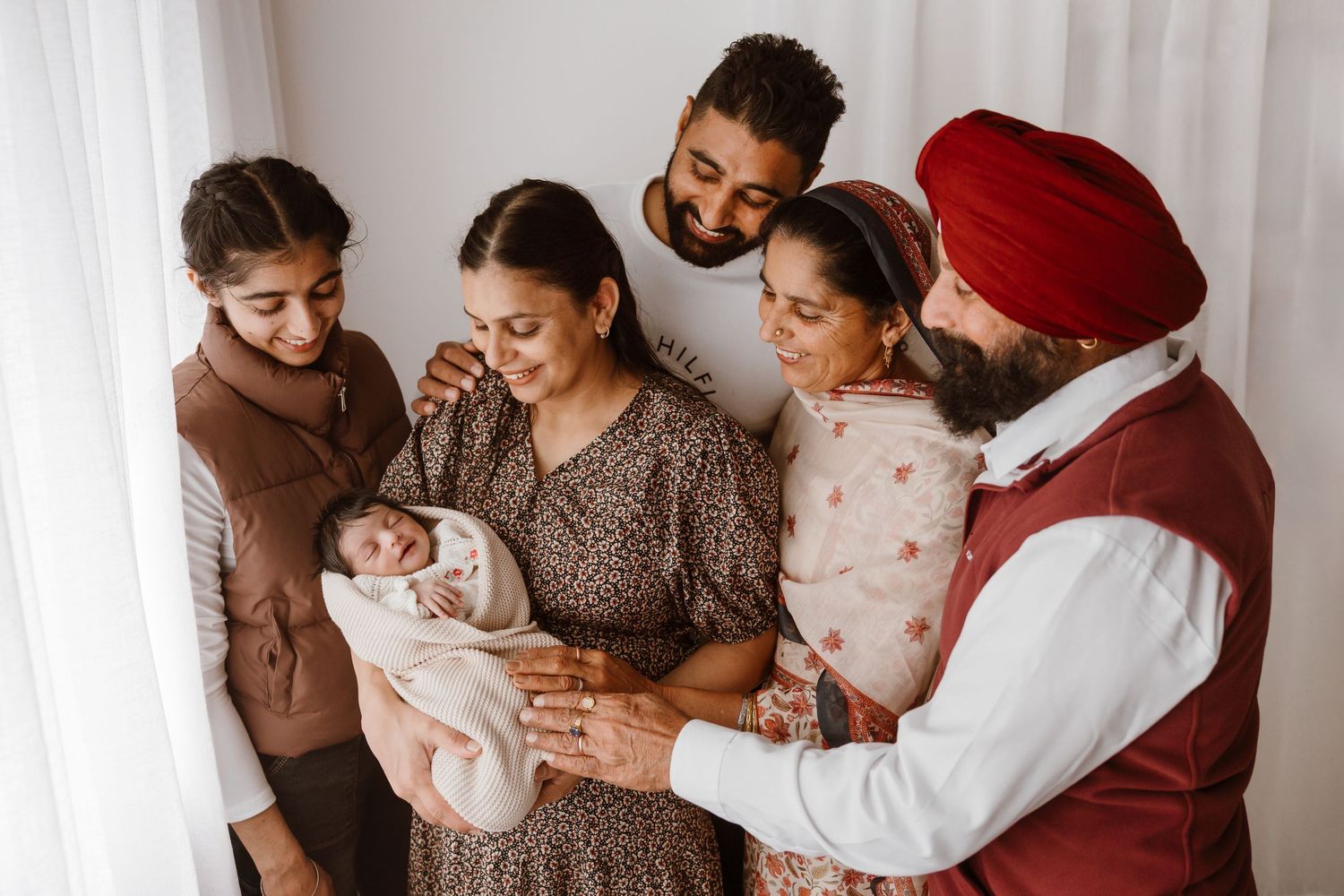 A heartwarming family portrait with their newborn baby against a white backdrop.
