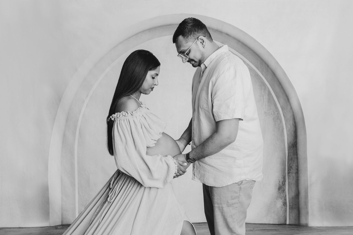 Couple sharing intimate moment in minimalist black and white maternity photo.