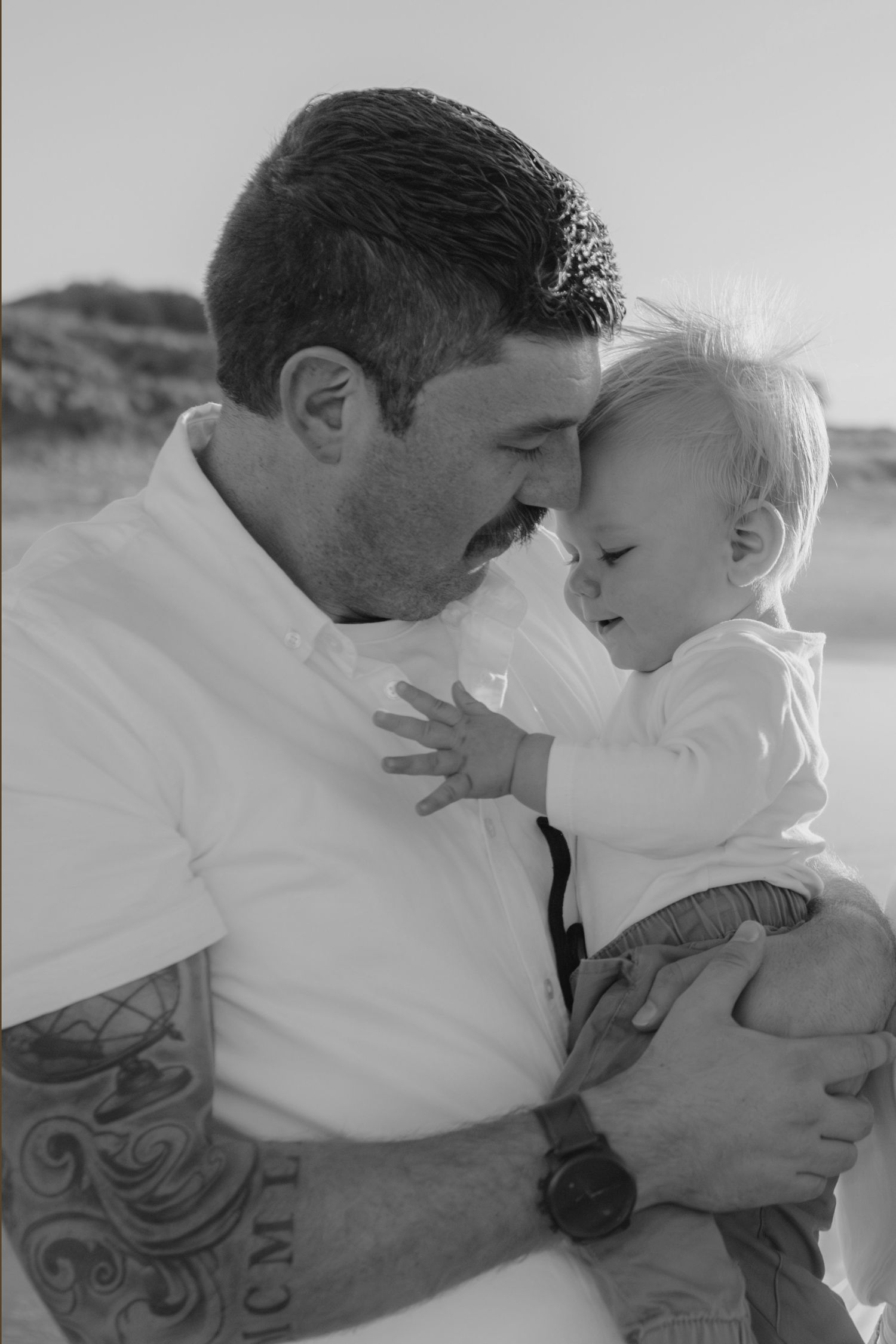 Intimate black and white portrait of tender parent-child moment outdoors.