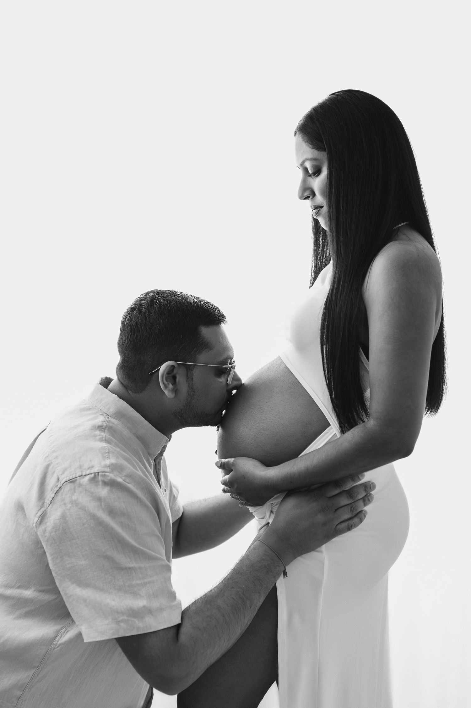Black and white maternity photo showing tender moment between expecting parents.