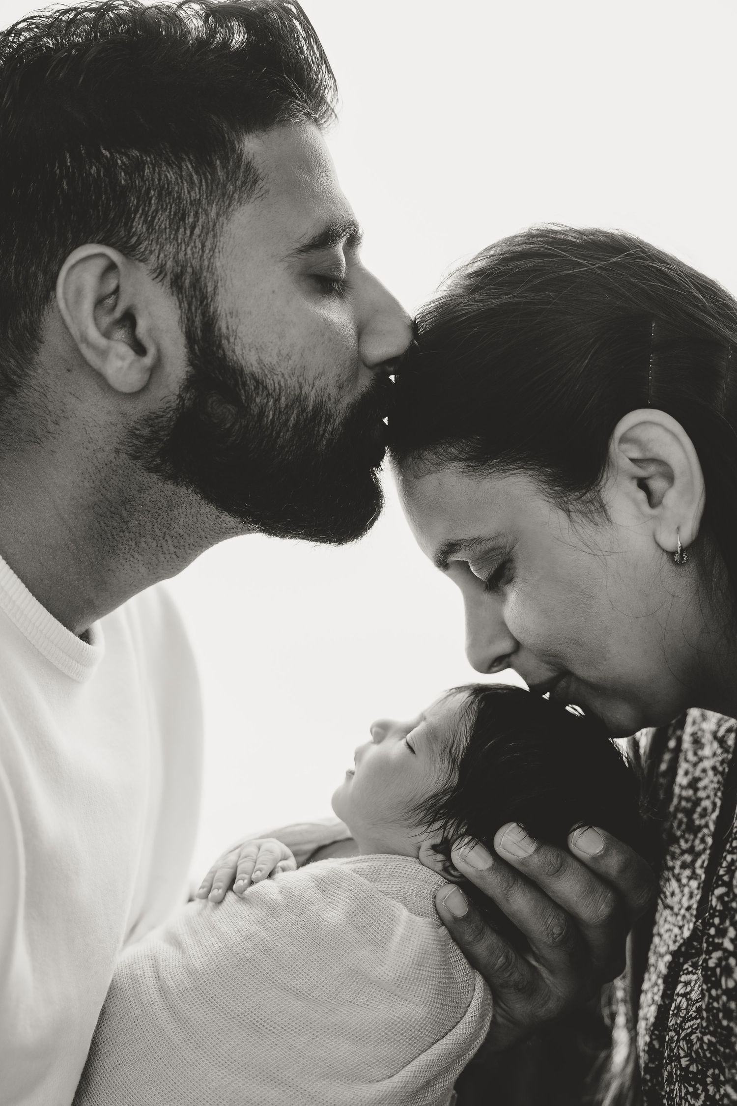 An intimate black and white family portrait with their newborn baby.