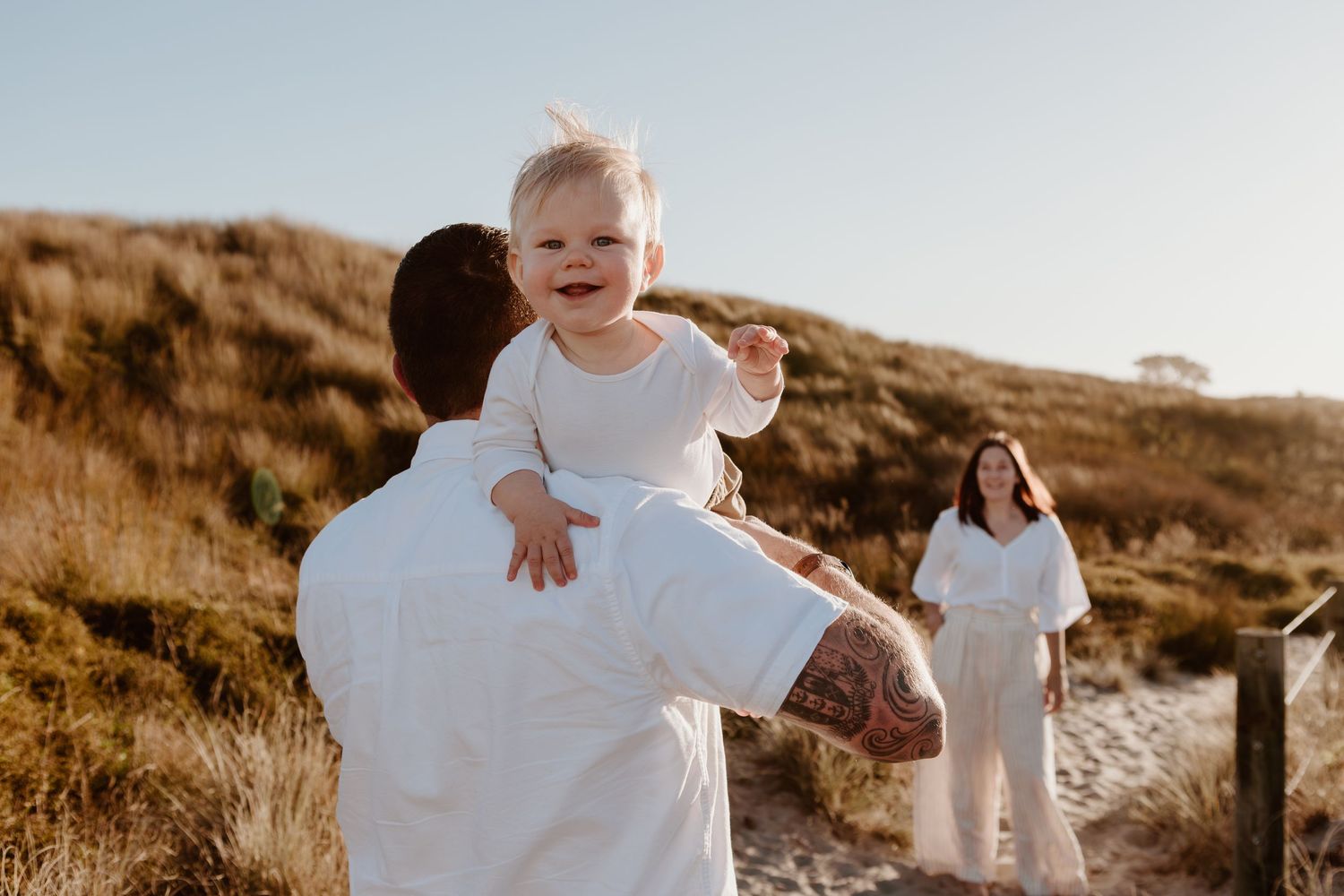 Joyful family moment captured in golden sunlight on coastal path.
