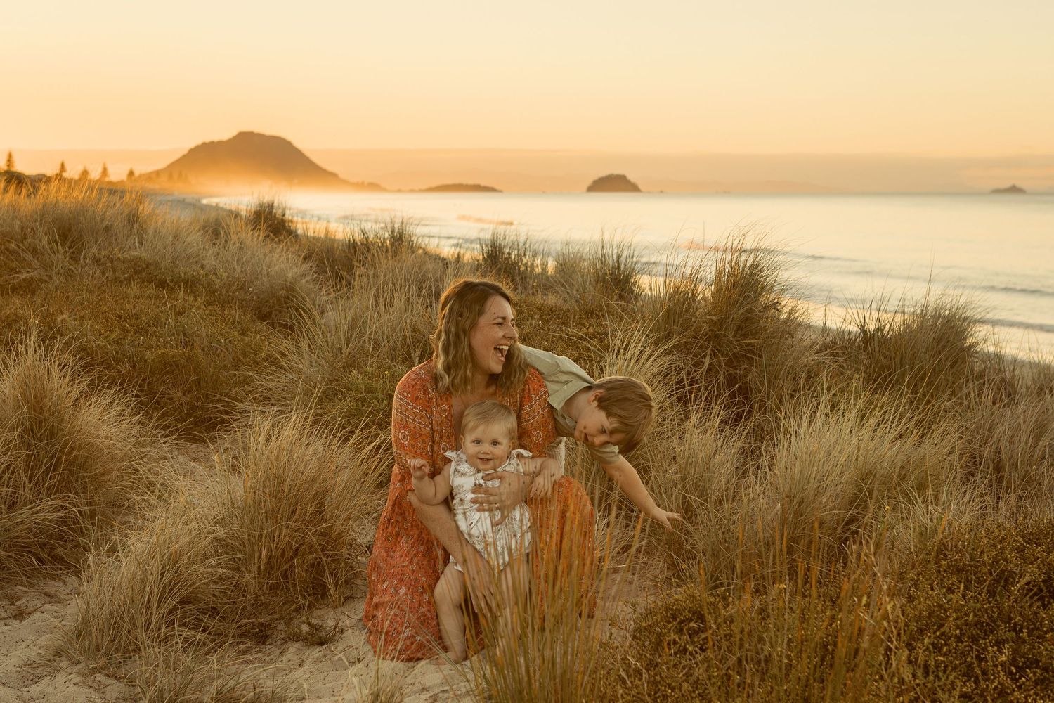 Sunset portrait session in coastal dunes with golden light and ocean views.