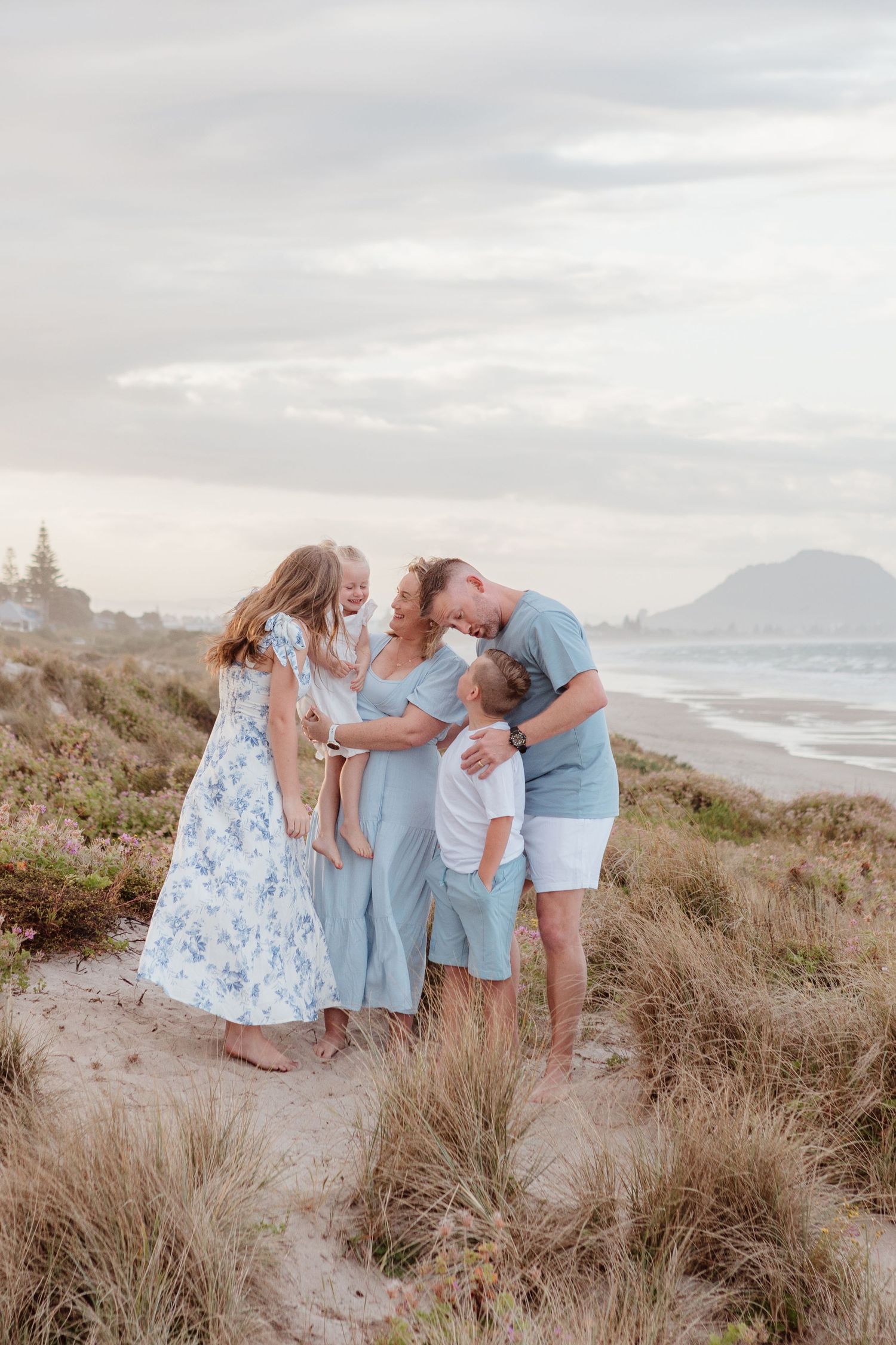 A tender family gathering on a coastal hillside overlooking the ocean at sunset.
