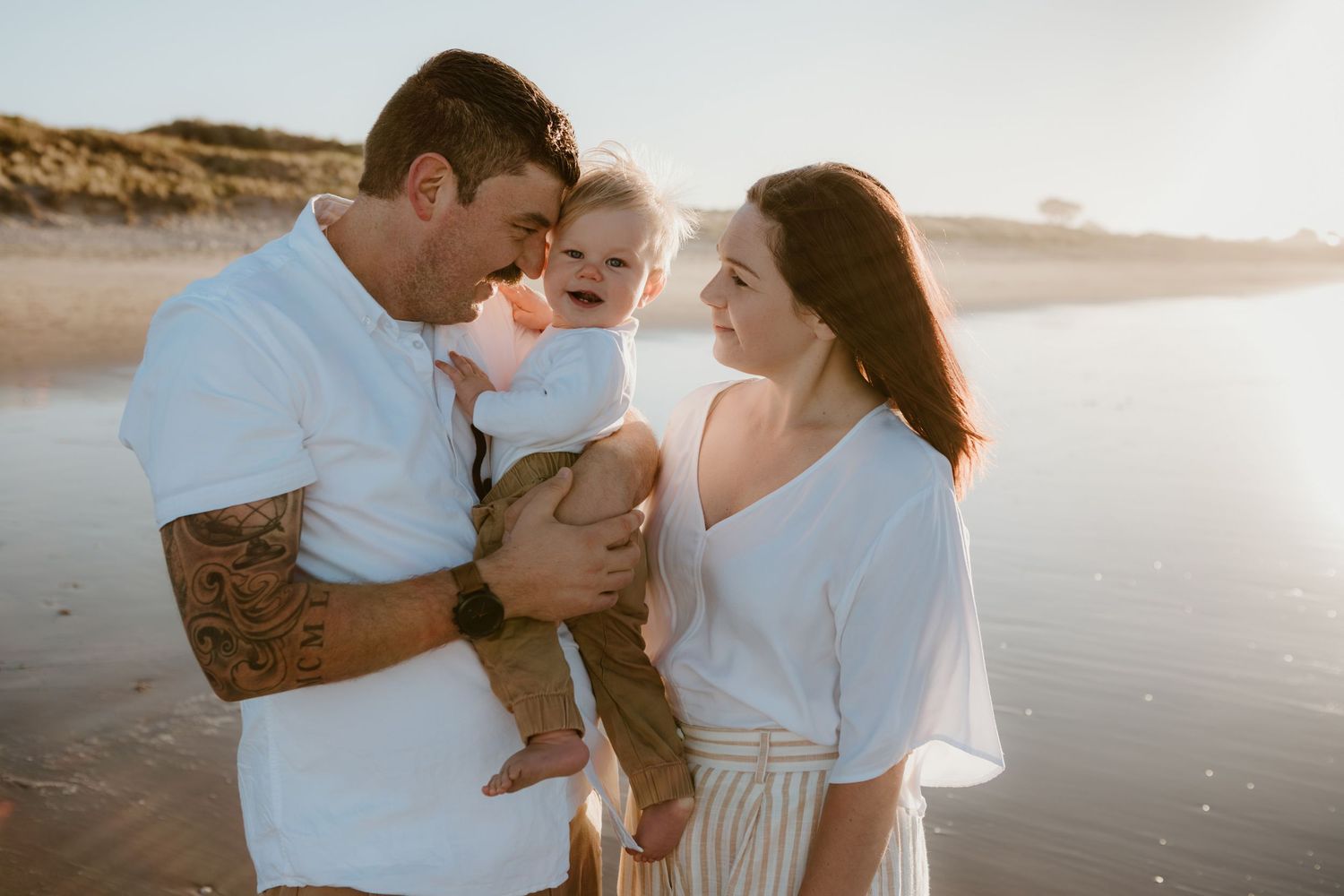 Family shares intimate moment together on sunny beach.
