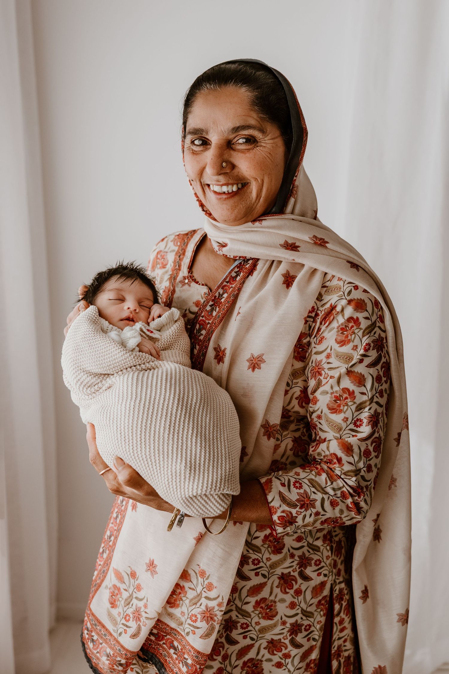 A tender portrait of mother and newborn baby in traditional Indian attire. Family newborn photoshoot Tauranga.