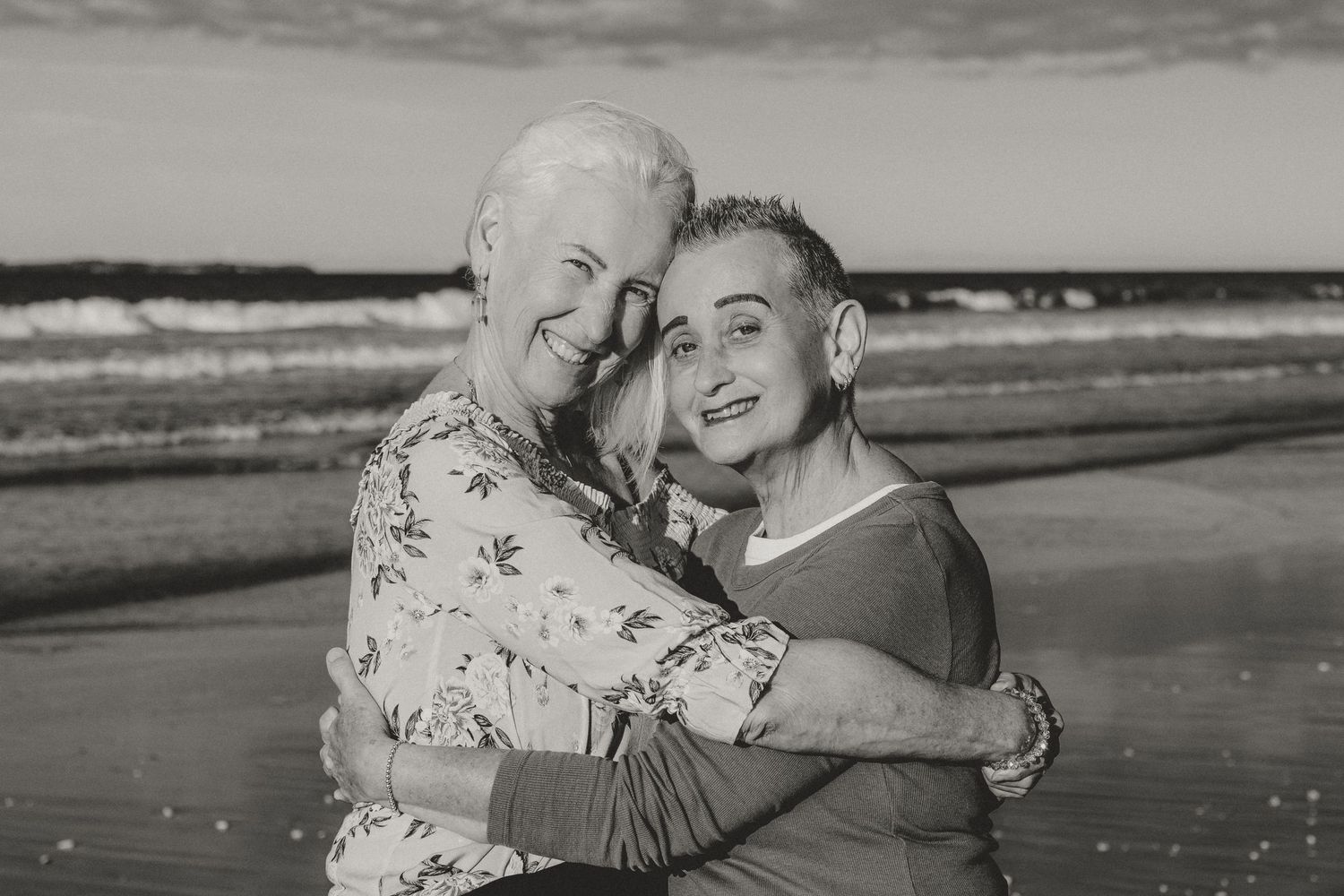 Black and white photos capturing joyful embraces and candid moments on a beach.