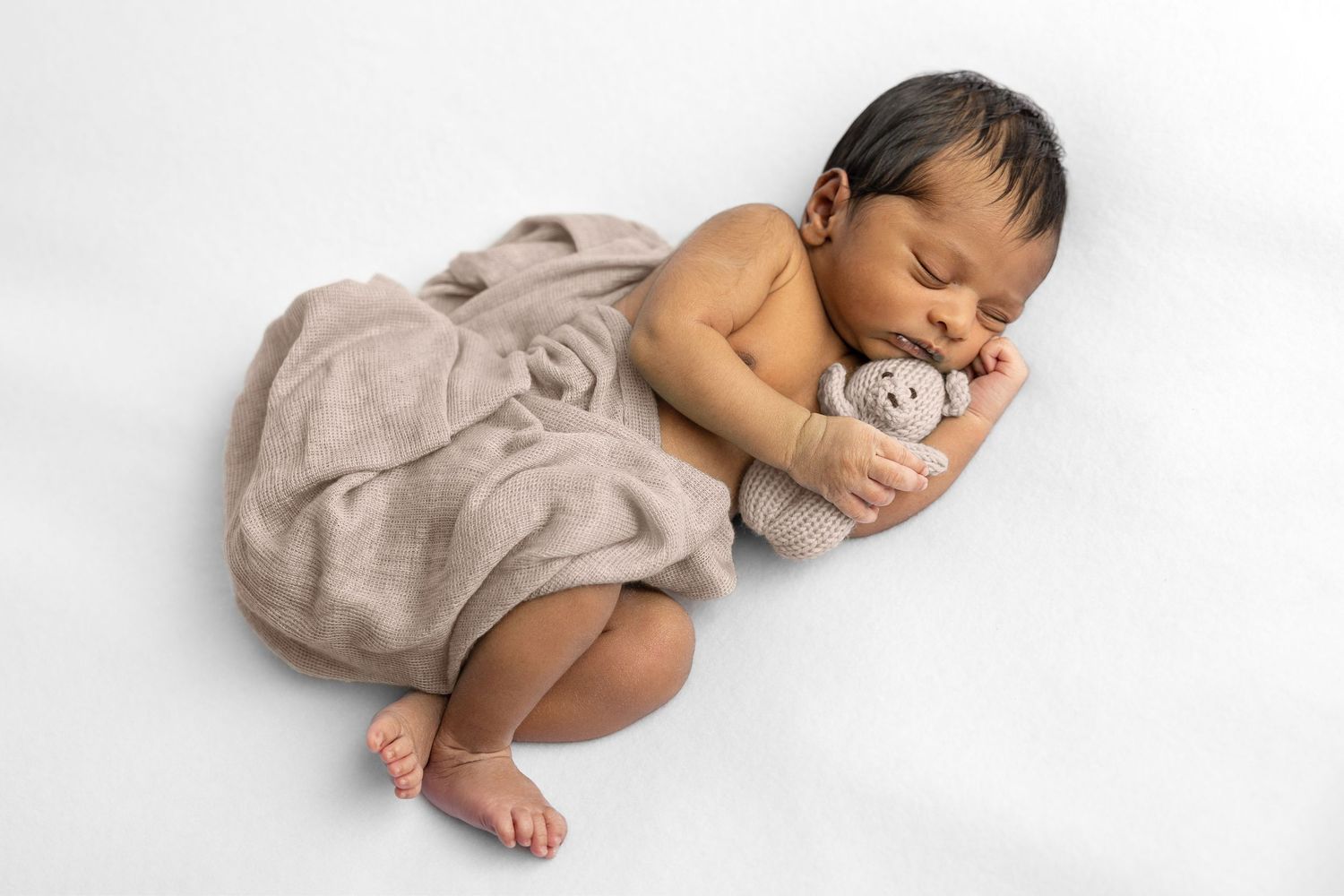 Peaceful sleeping newborn in beige wrap during studio photography session.