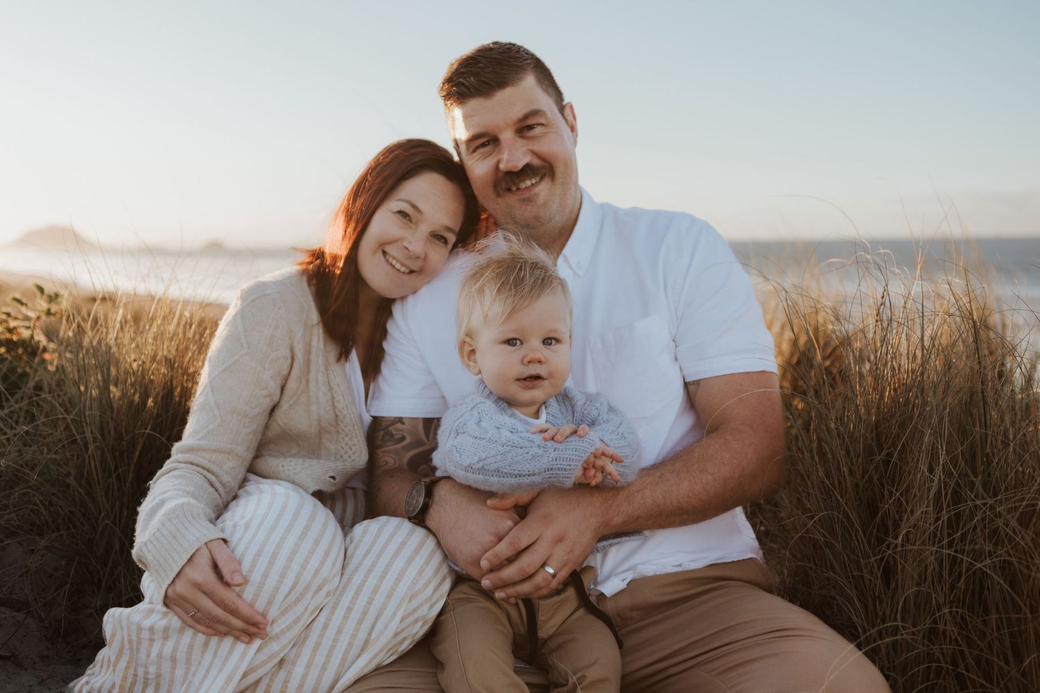 Family portrait at sunset with coastal backdrop and natural lighting.