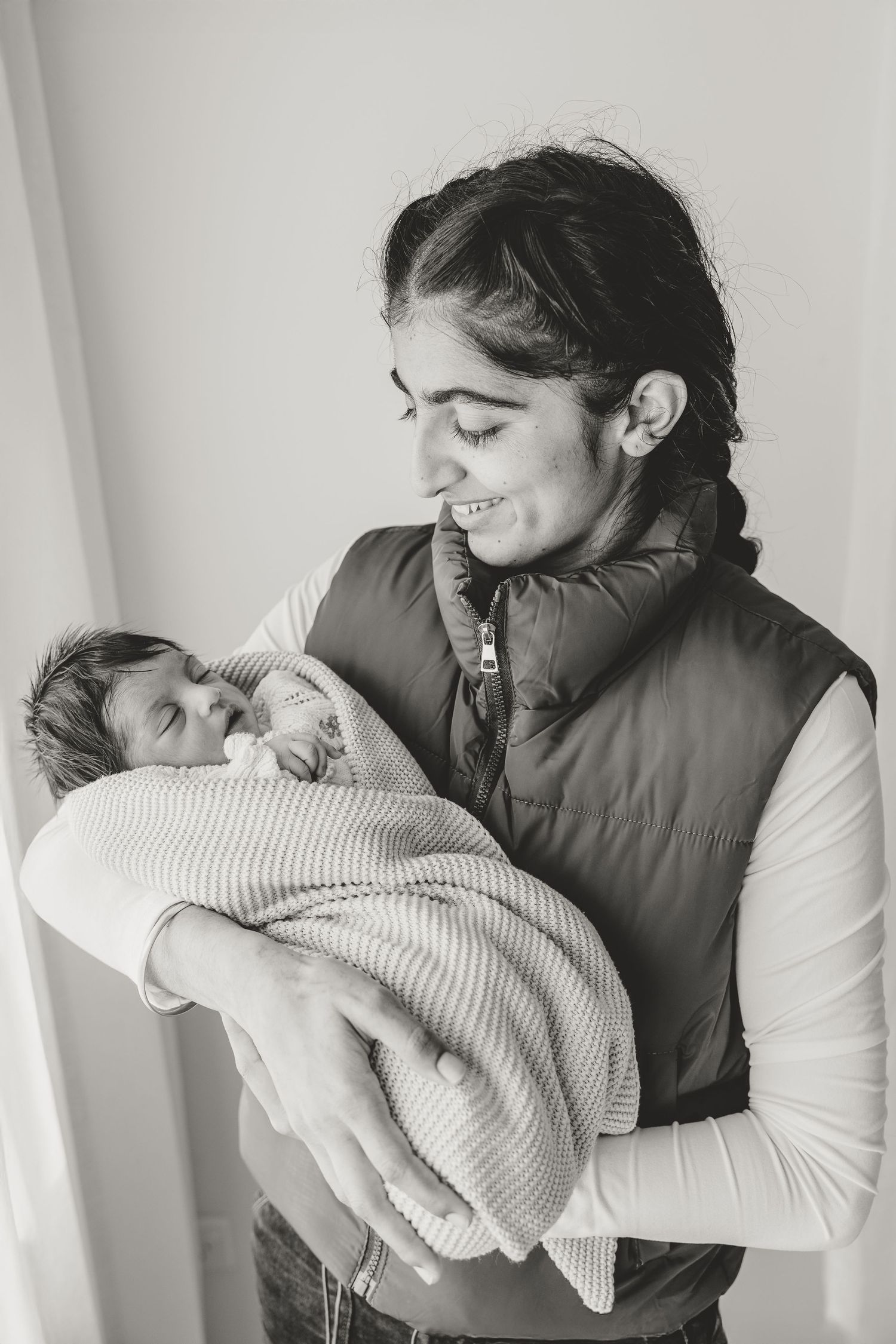 A tender moment between parent and newborn baby wrapped in a cozy white blanket.