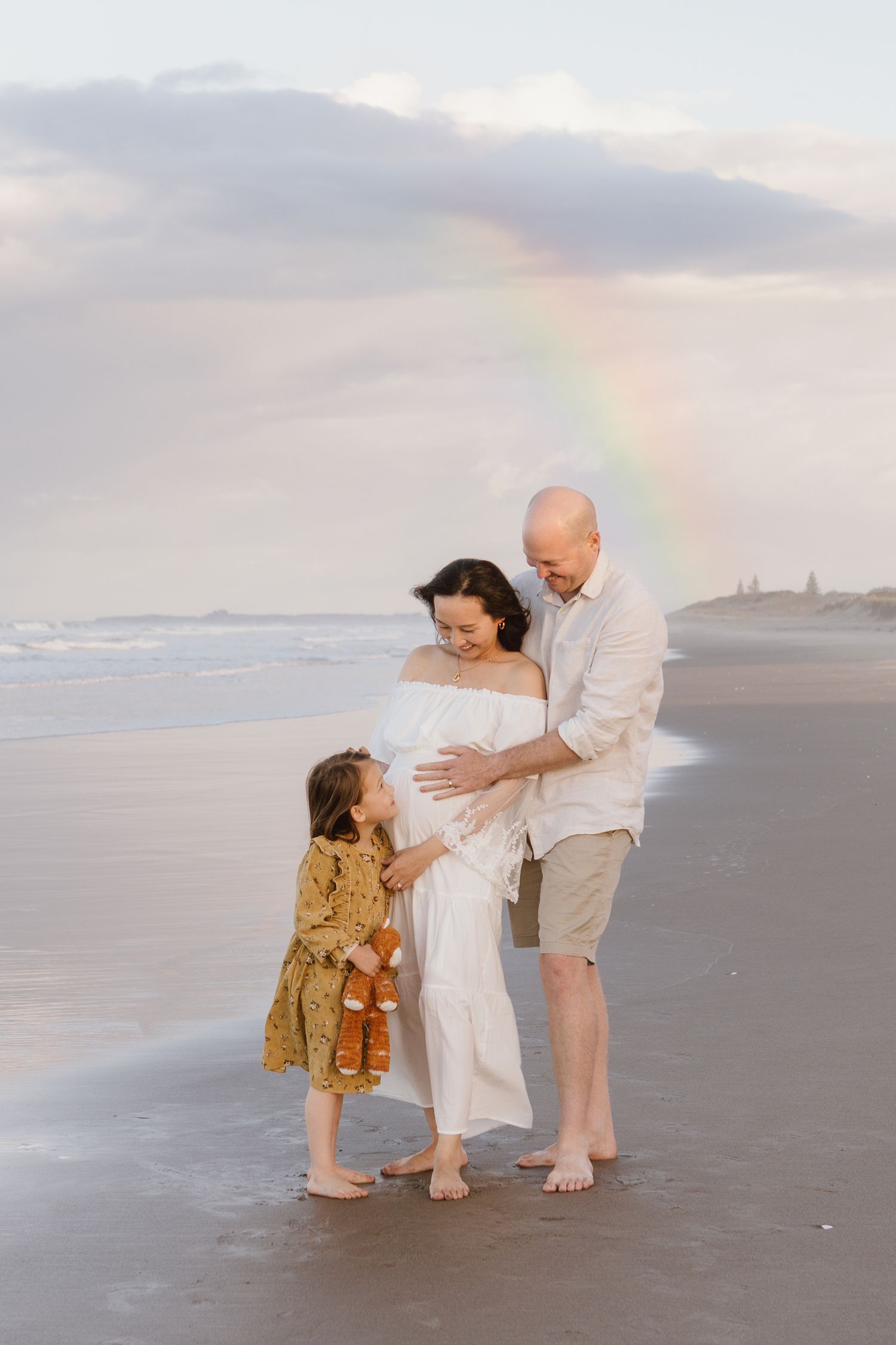 Beach family photoshoot at sunset with ocean backdrop.
