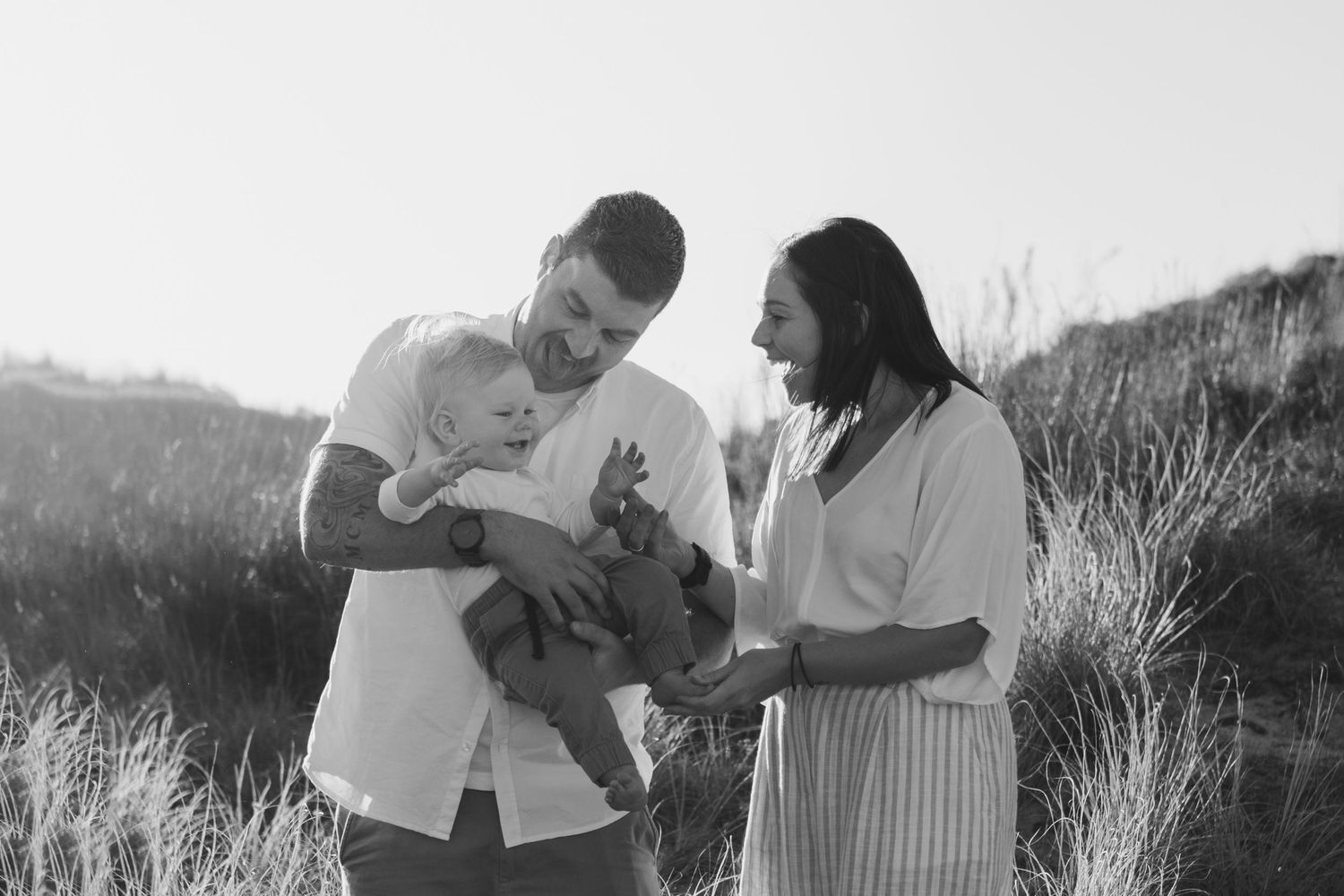 A family sharing a tender moment together in a grassy field at sunset.