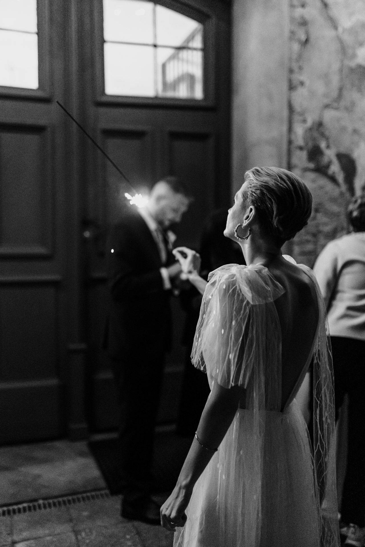 Romantic black and white photo of sparklers illuminating evening wedding celebration.