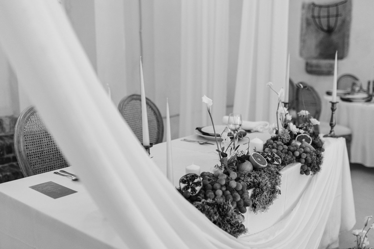 Black and white photo of wedding table decor through flowing white fabric.