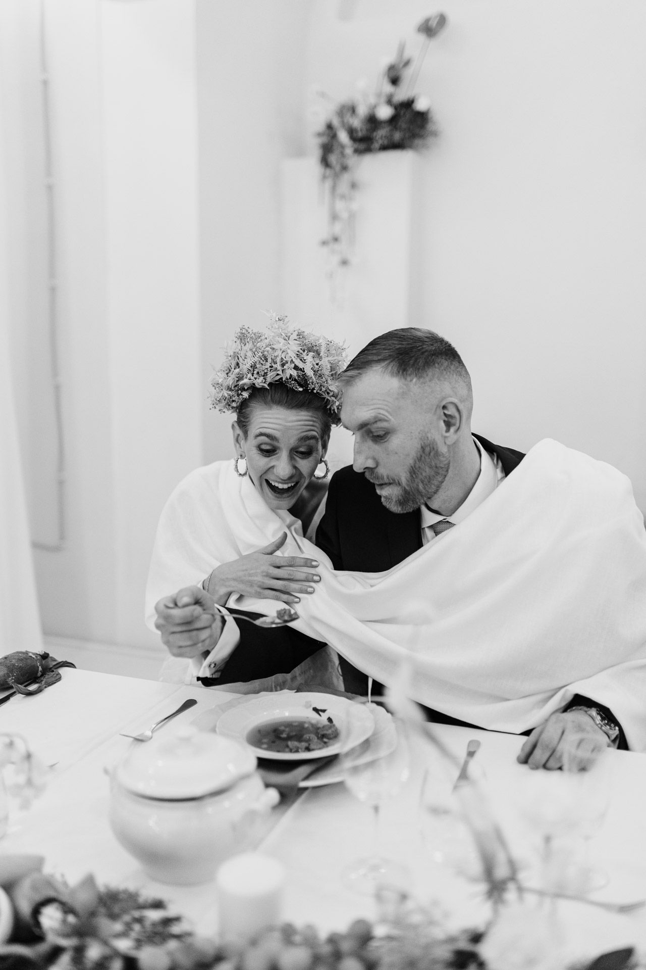 Black and white photo of couple sharing intimate moment while dining at decorated table.