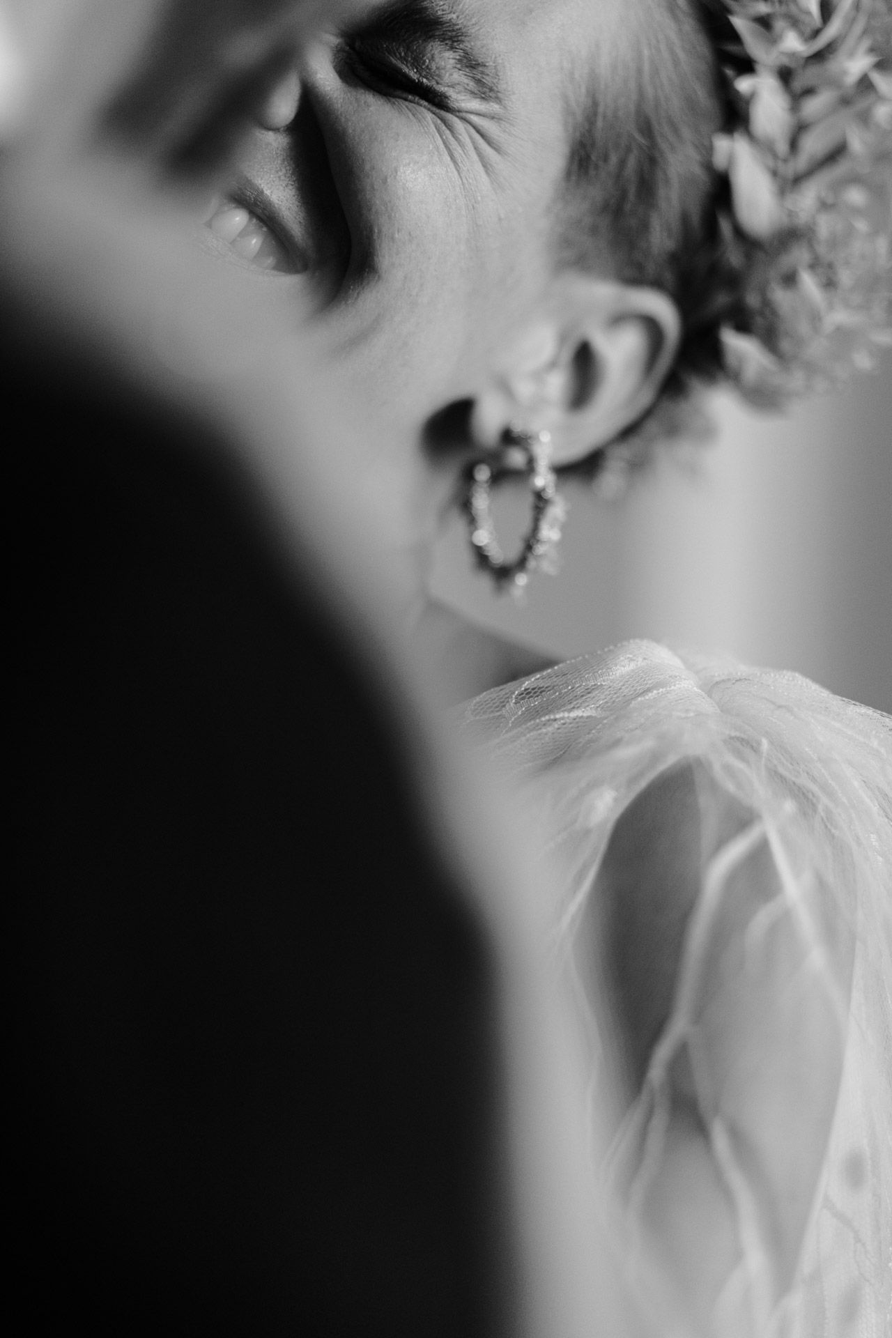 Artistic black and white close-up of bridal jewelry and delicate dress fabric.
