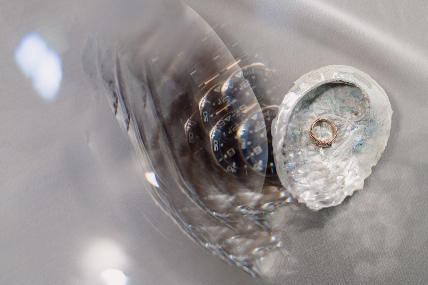 Wedding rings photographed in crystal glassware with reflective light.