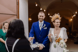 Wedding celebration in arched venue with string lights and joyful reception atmosphere.