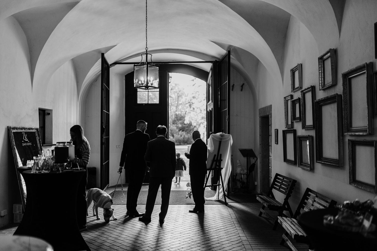 Black and white archway interior with framed artwork and silhouettes in natural light.