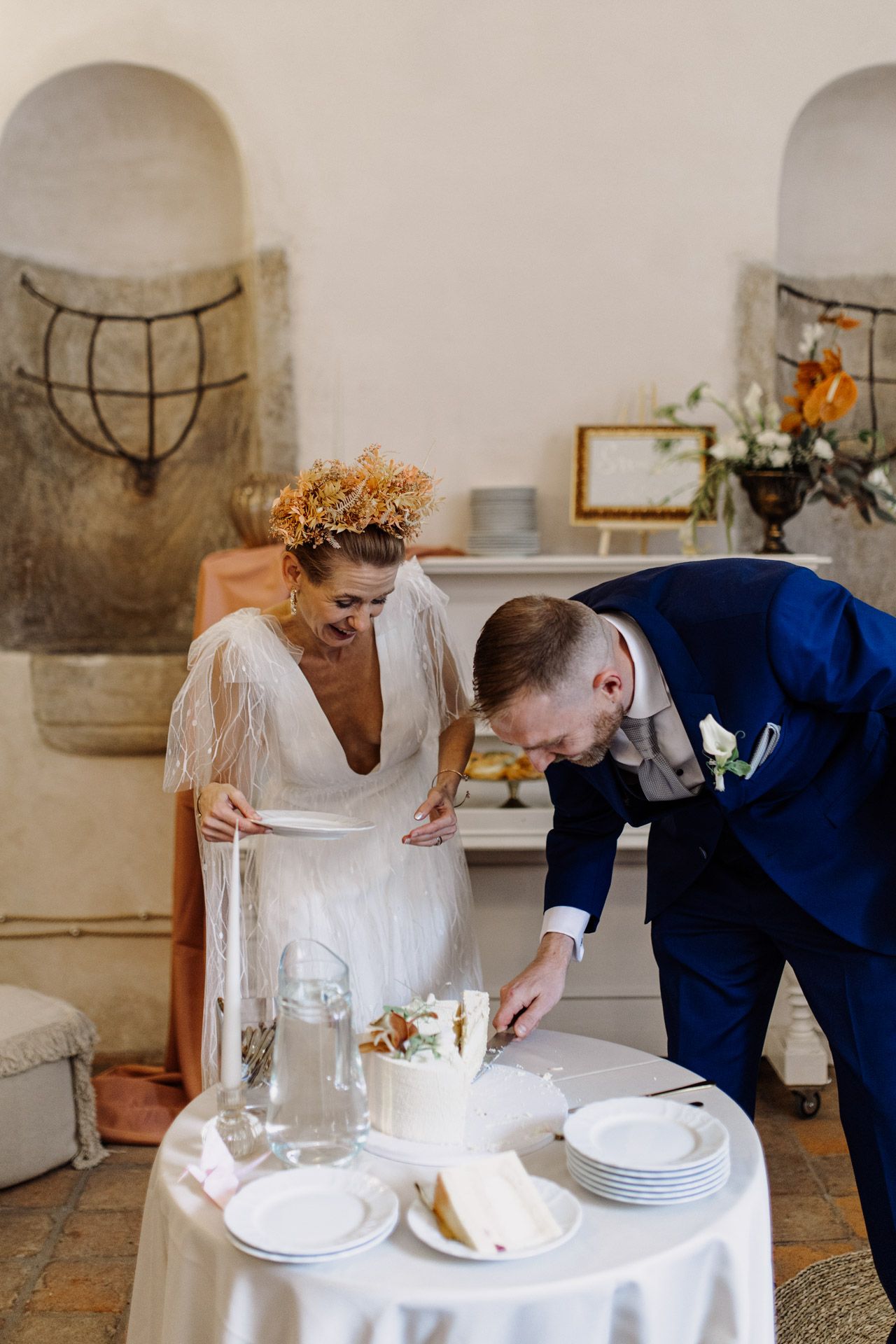 Couple arranging place settings at intimate dining table in rustic venue.