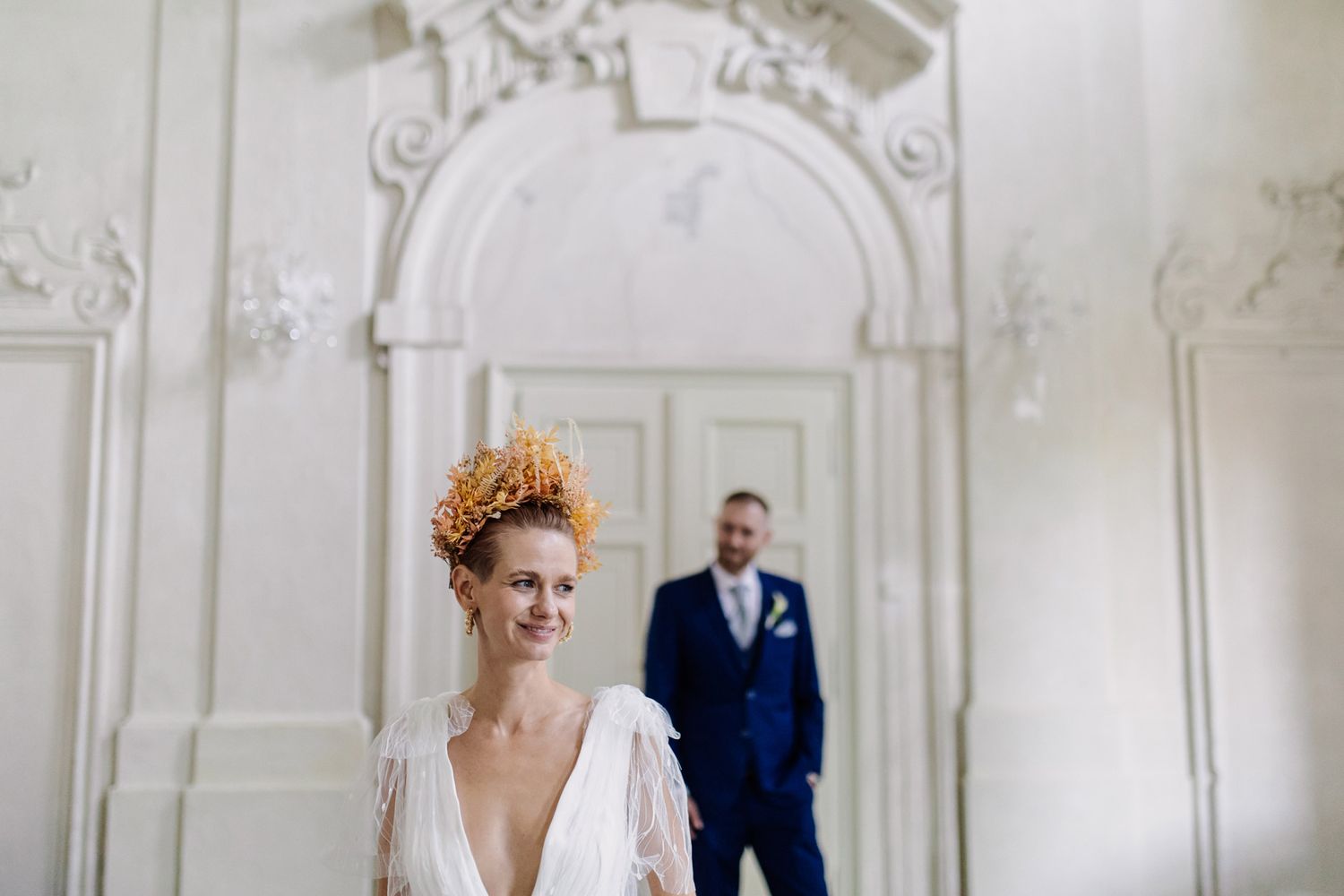 Intimate wedding portrait in grand white room with decorative architectural details.