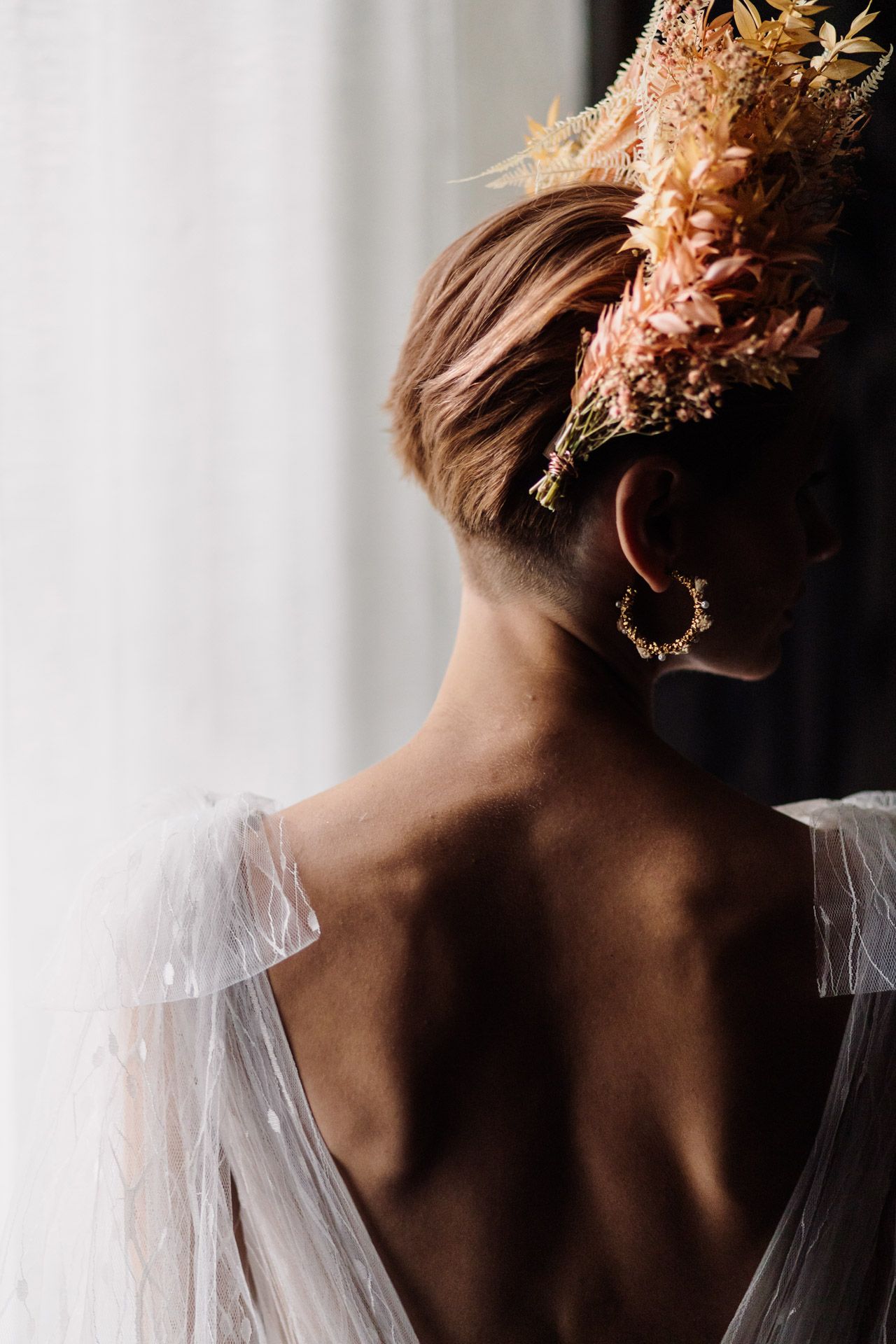 Close-up of dried floral headpiece and delicate sheer fabric against white background.