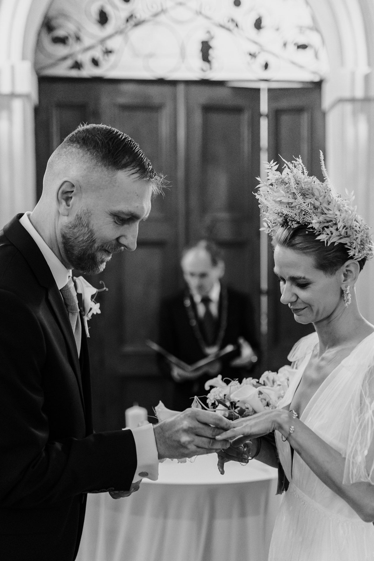 Intimate black and white moment during ring exchange at wedding ceremony.
