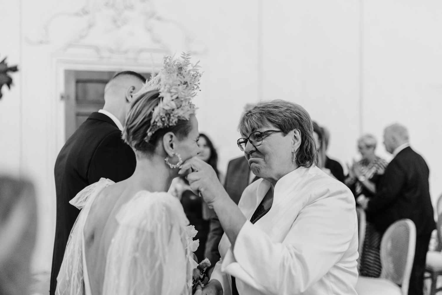 Black and white candid moment of wedding guests sharing conversation.