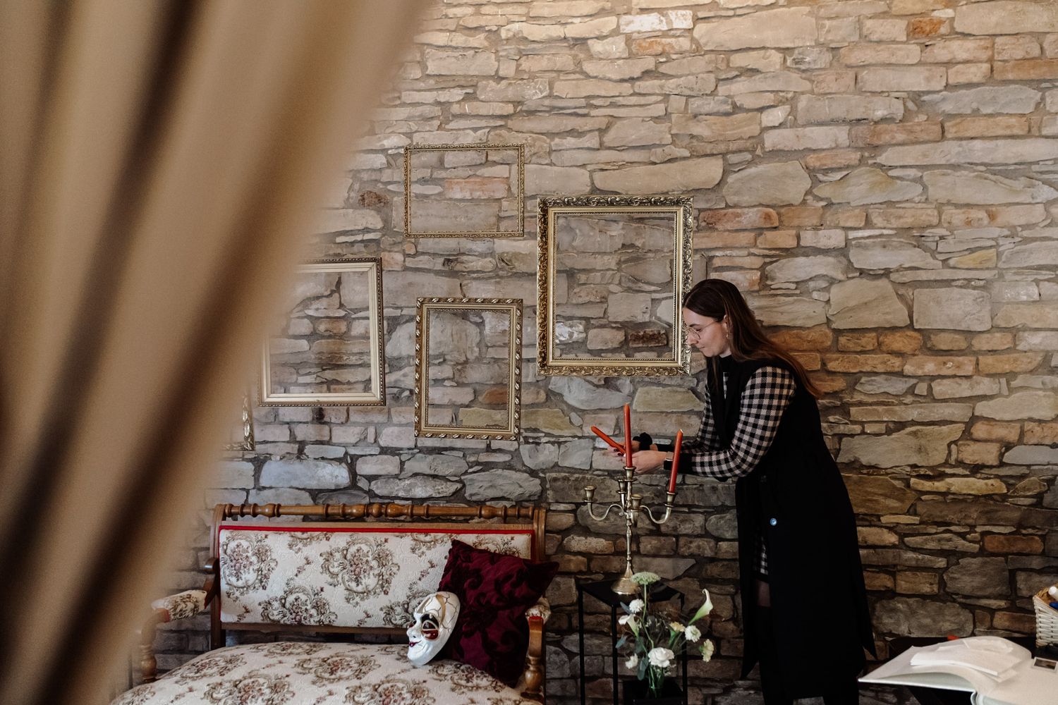Decorative vintage setting against stone wall with antique frames and candle arrangements.
