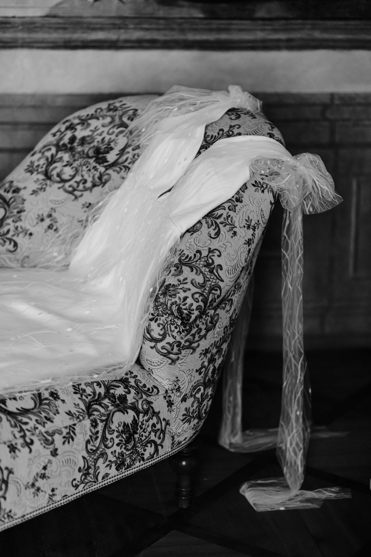 Vintage floral chaise lounge with delicate white veil draped across it in black and white.