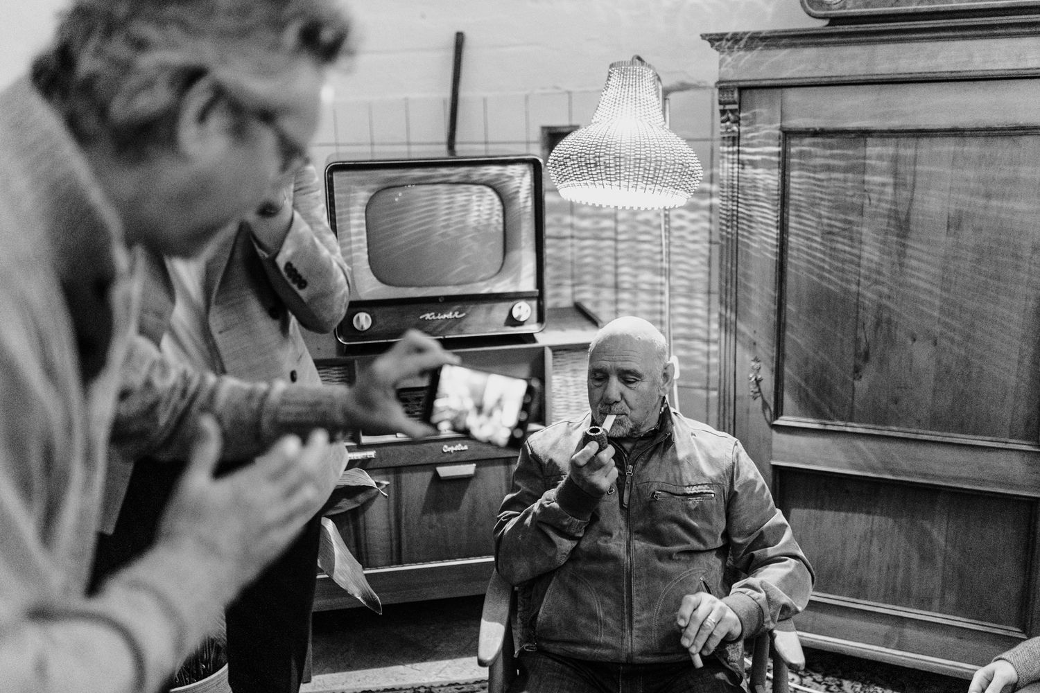 Candid black and white photo of musicians performing at casual gathering.