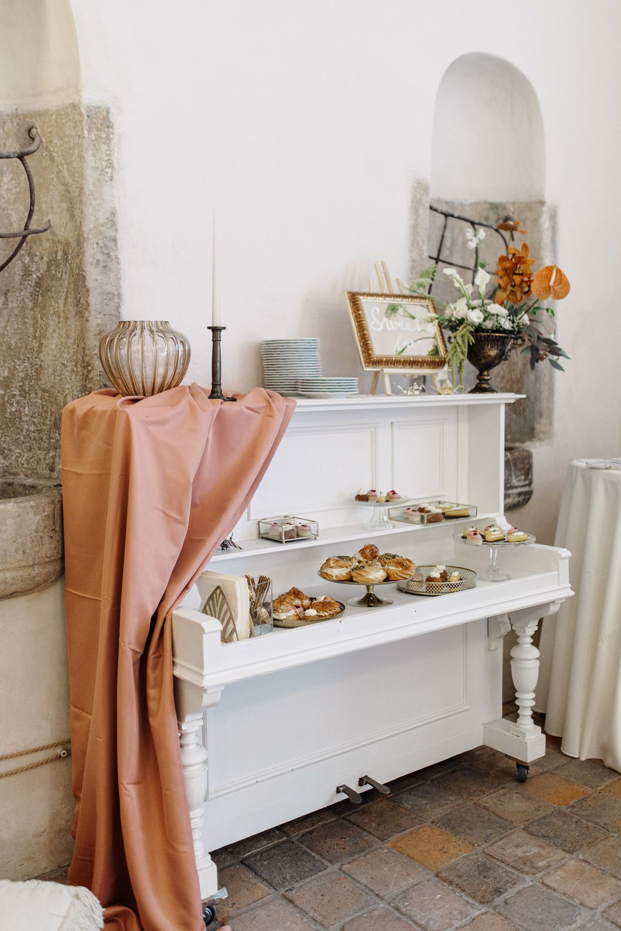 White buffet table with peach draping and elegant appetizer display.