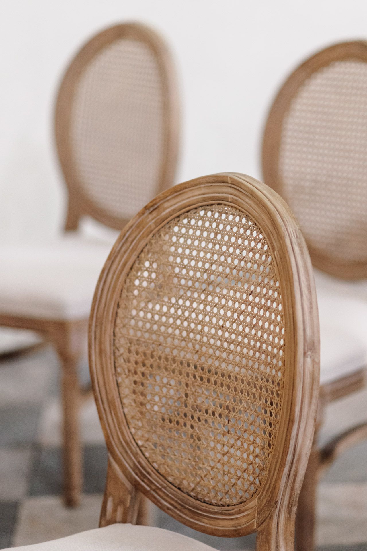 Close-up detail of a cane-back French dining chair with woven rattan pattern.