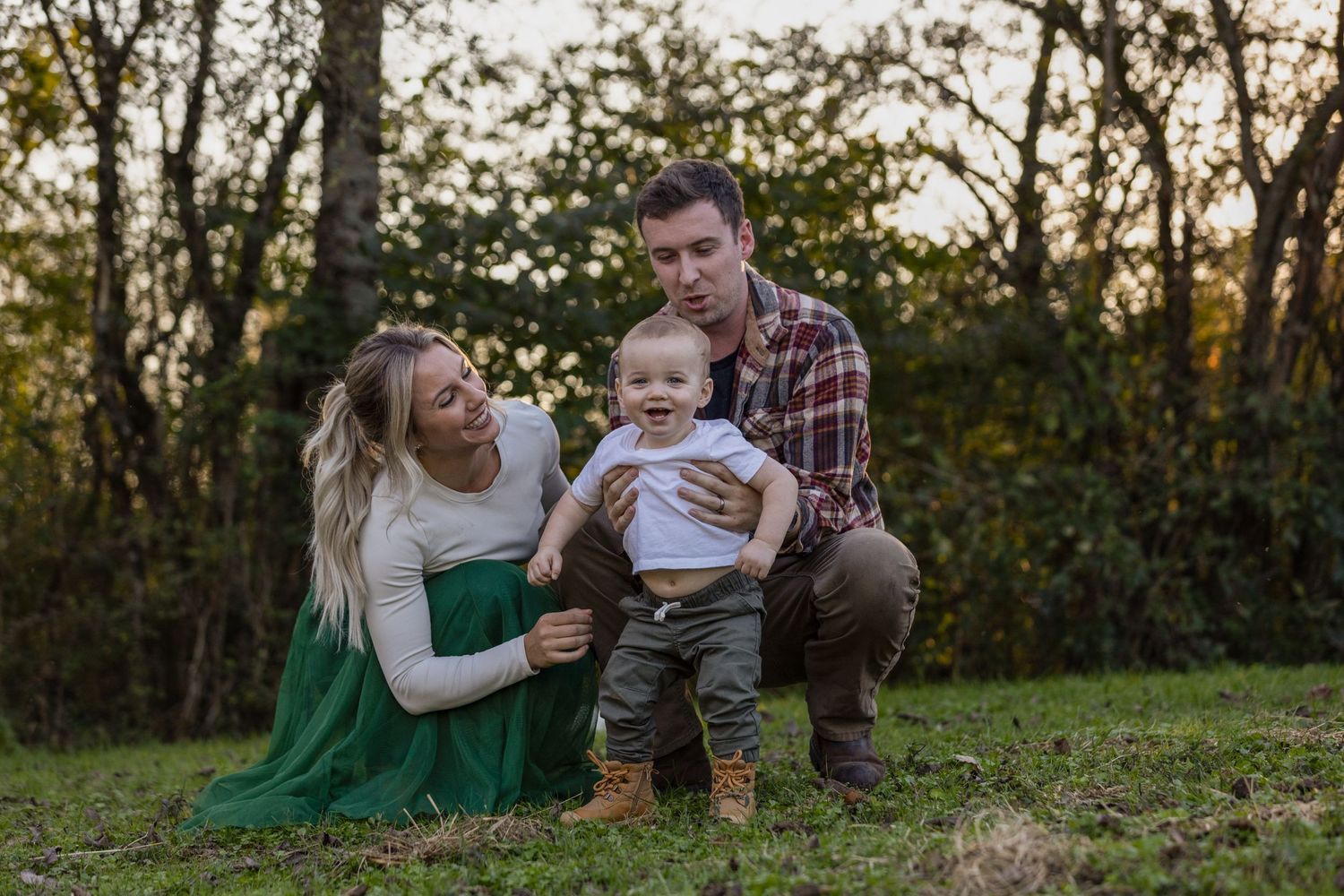 A family shares smiles while posing together on grass during a fall photo session.