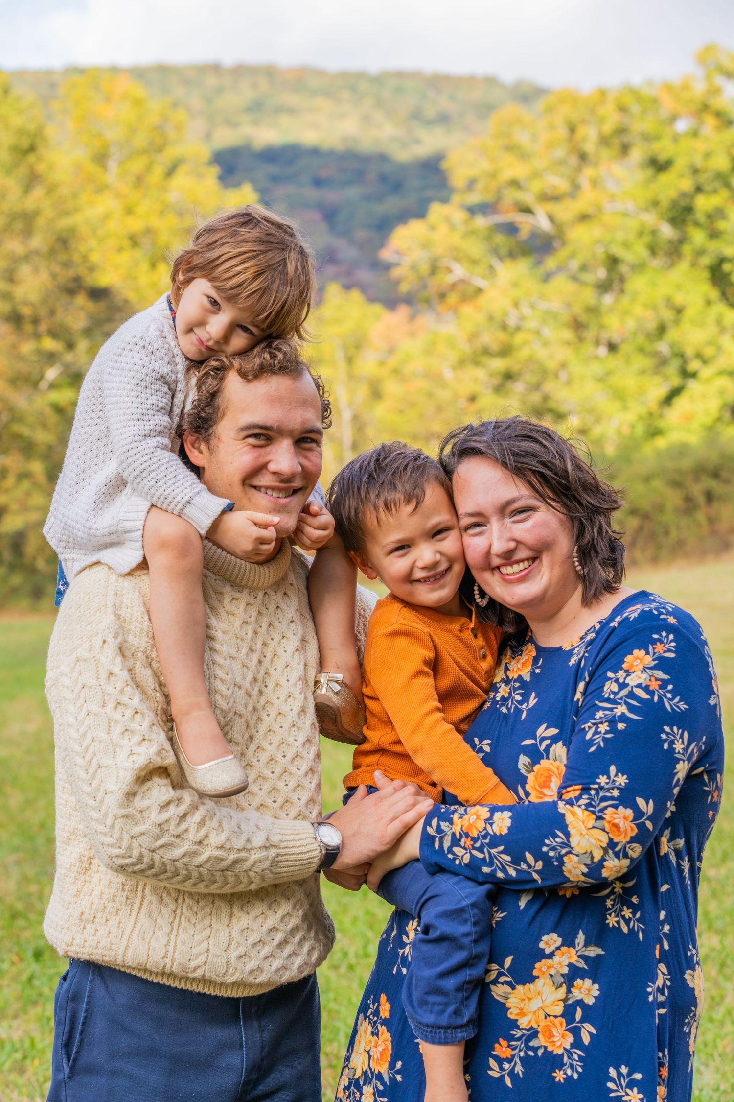 A joyful family portrait outdoors with vibrant autumn colors in the background.