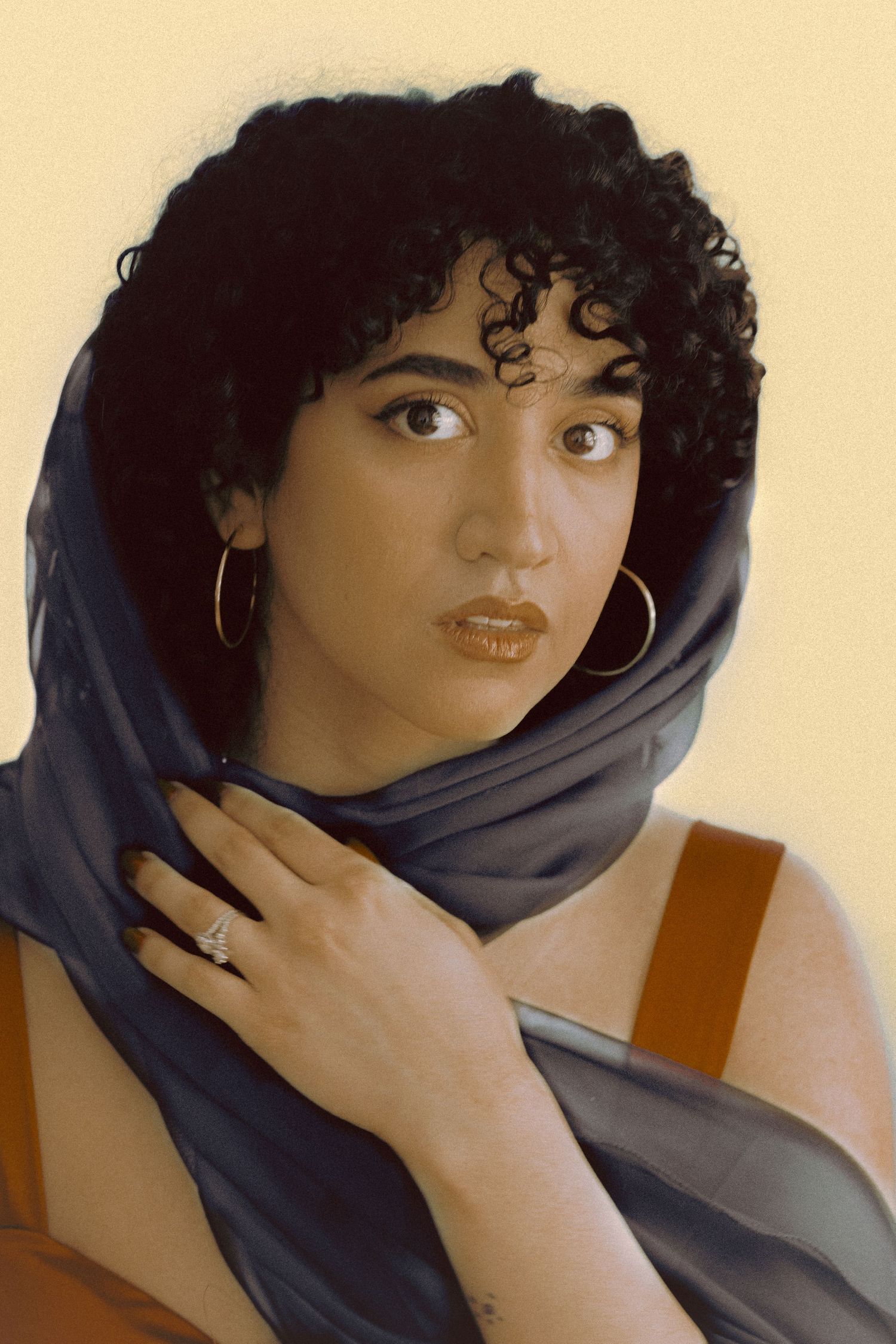 Portrait of Farin, an Iranian woman, with ahead scarf around her curly hair, edited to look like a painting.