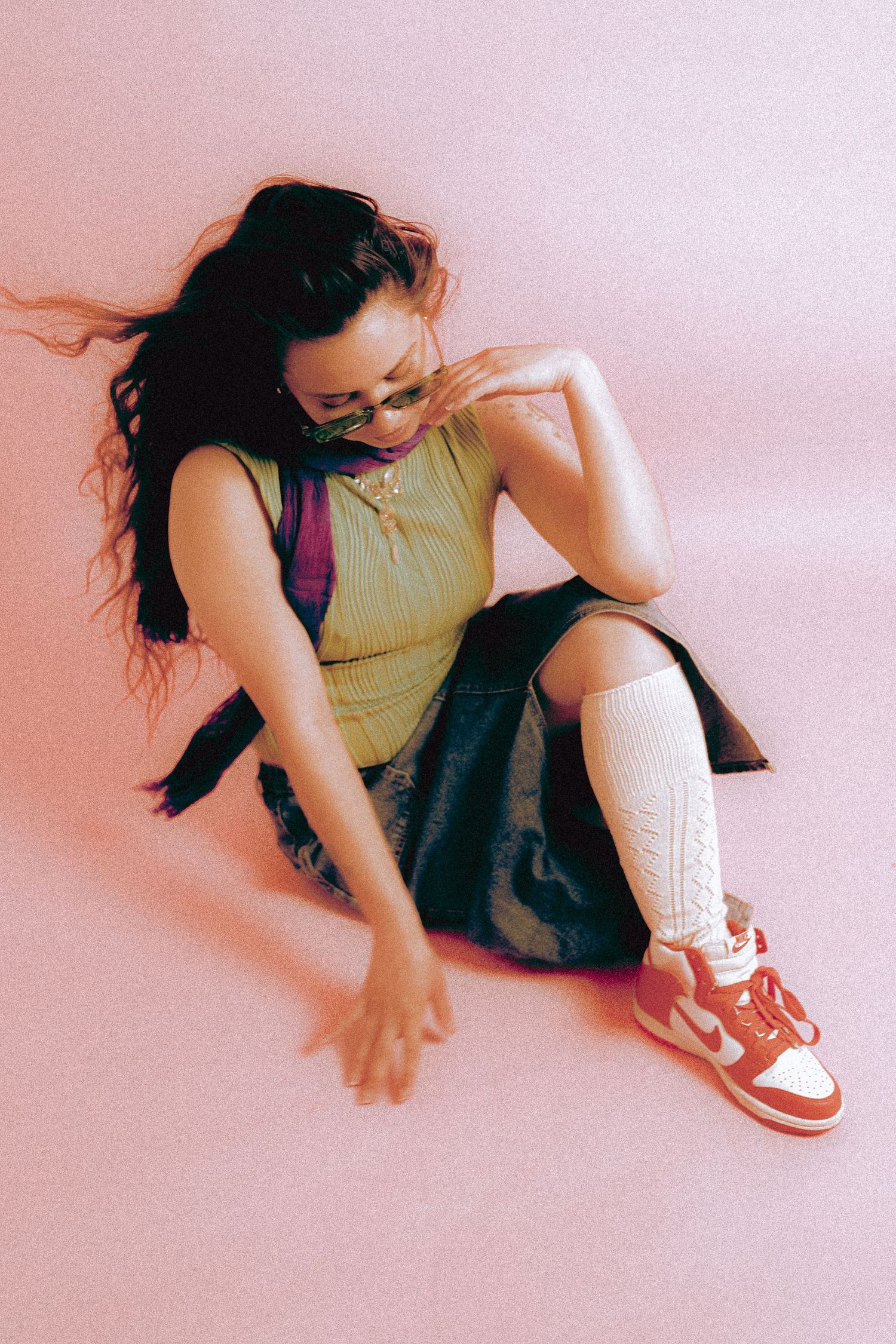 Portrait of a woman sitting in a pink backdrop, photographed at Sixteen Eleven Studios in Toronto