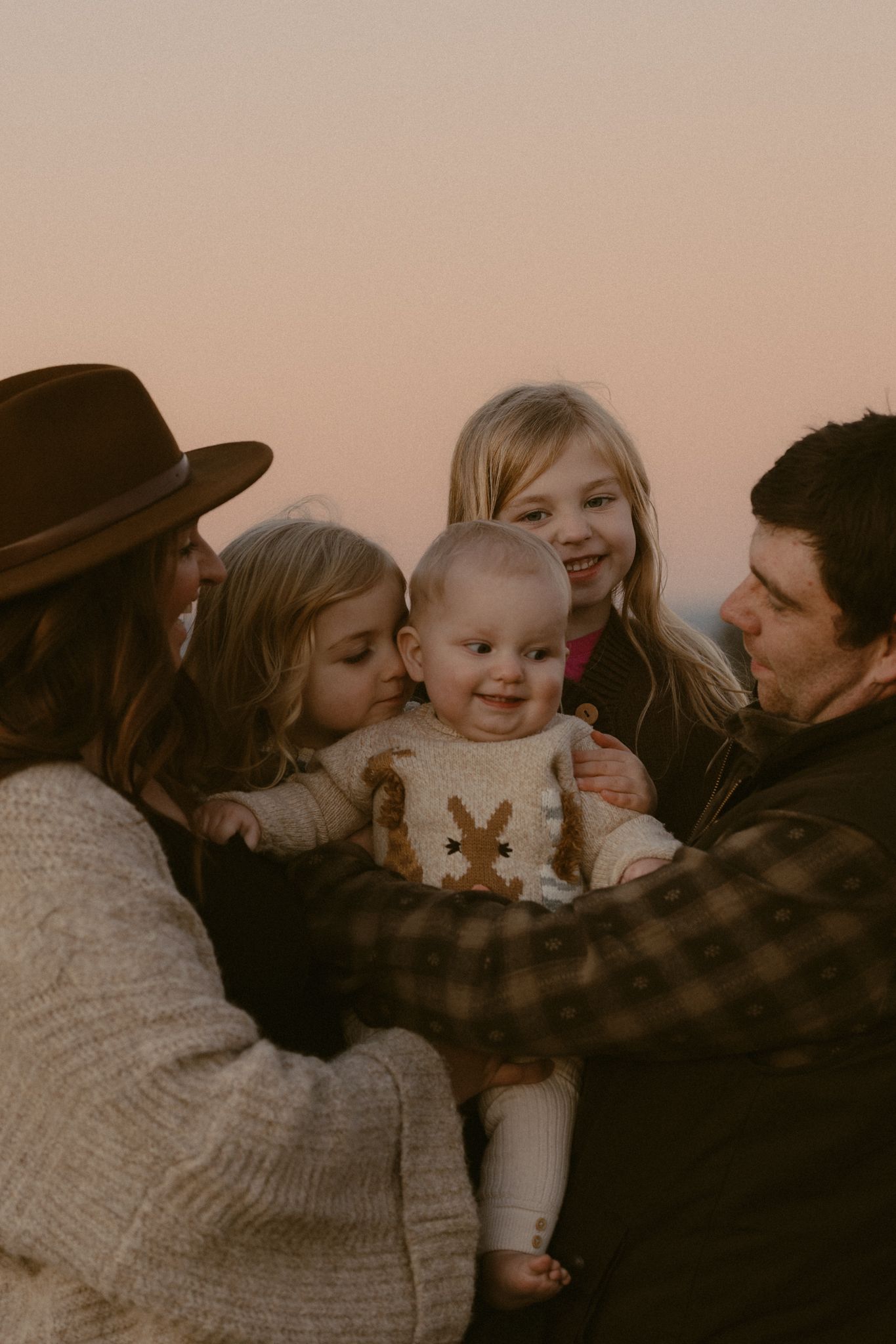 A heartwarming collage of family moments shows people embracing and interacting with a baby in warm sepia tones.