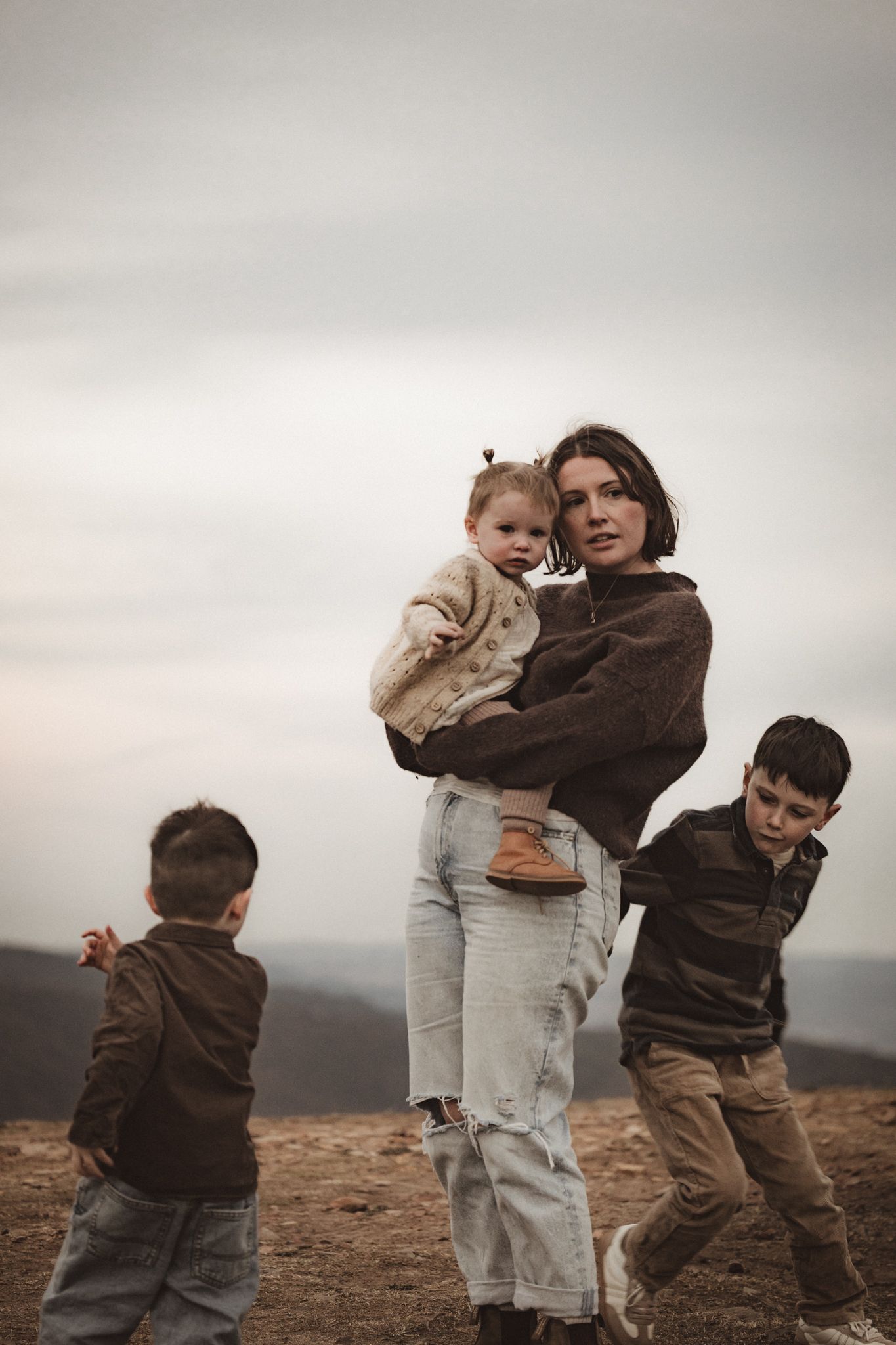Family standing together on desert hillside during golden hour against an overcast sky.